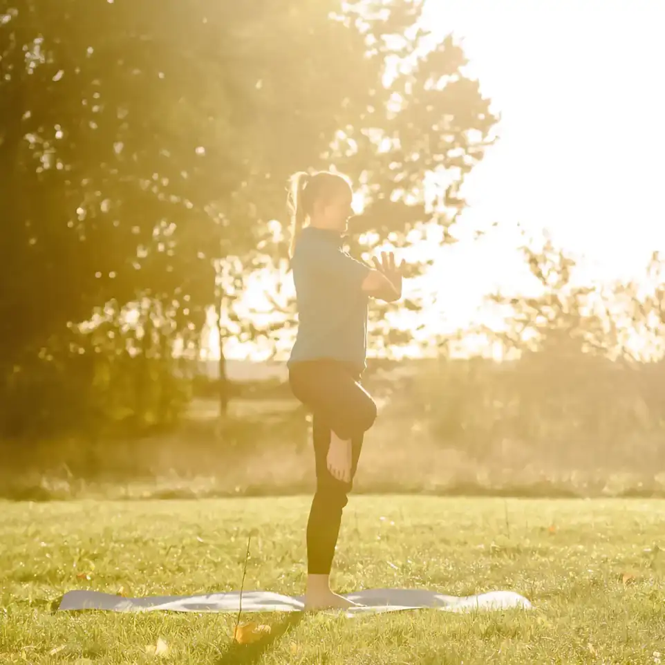 Eine Frau macht im Sonnenlicht Yoga.