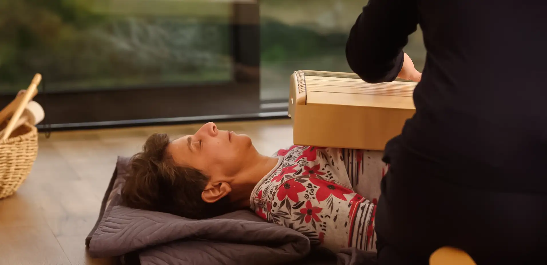 Eine Patientin erhält eine Therapie. Sie liegt auf dem Rücken, auf ihr liegt ein Holzbrett.