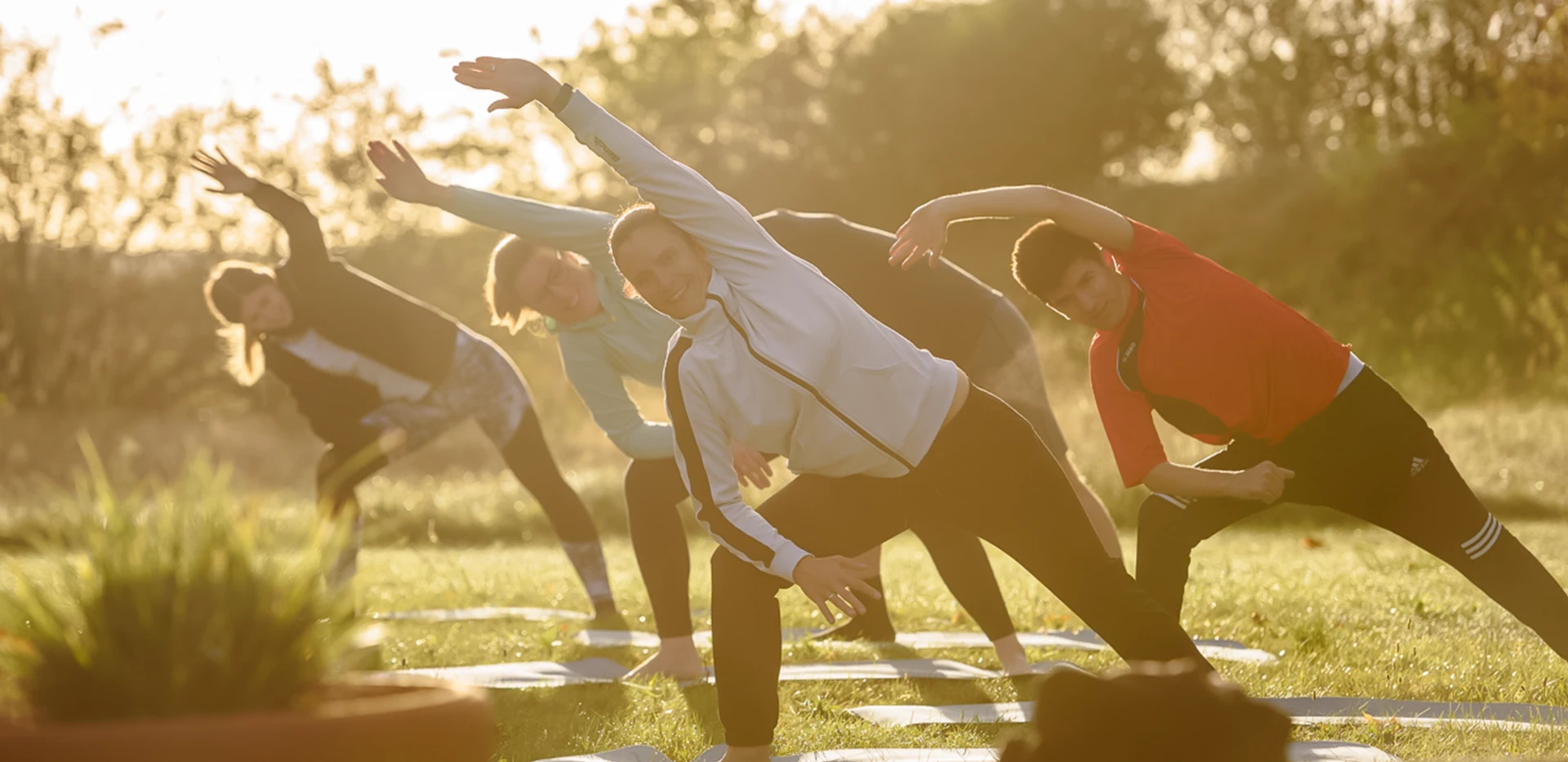 Mehrere Sportler, die an Depressionen leiden, machen draußen gemeinsam Yoga