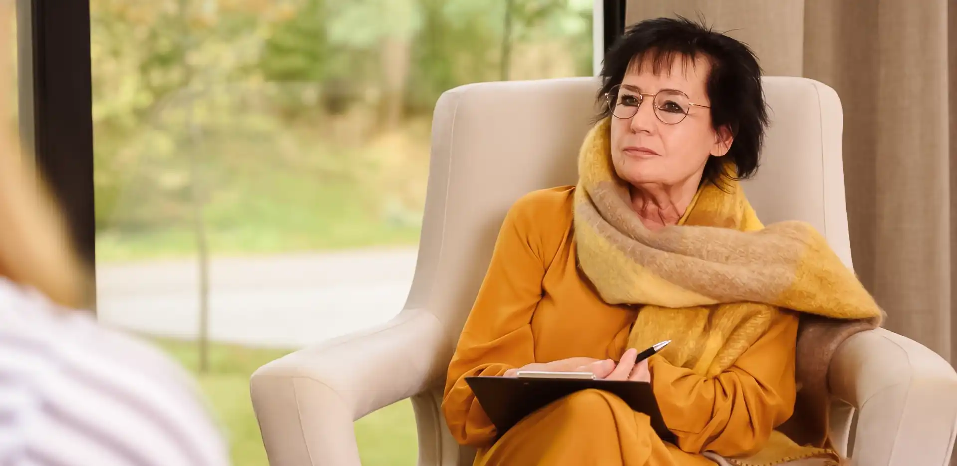 Eine Psychotherapeutin sitzt im Gespräch mit einer Patientin und hört ihr zu.