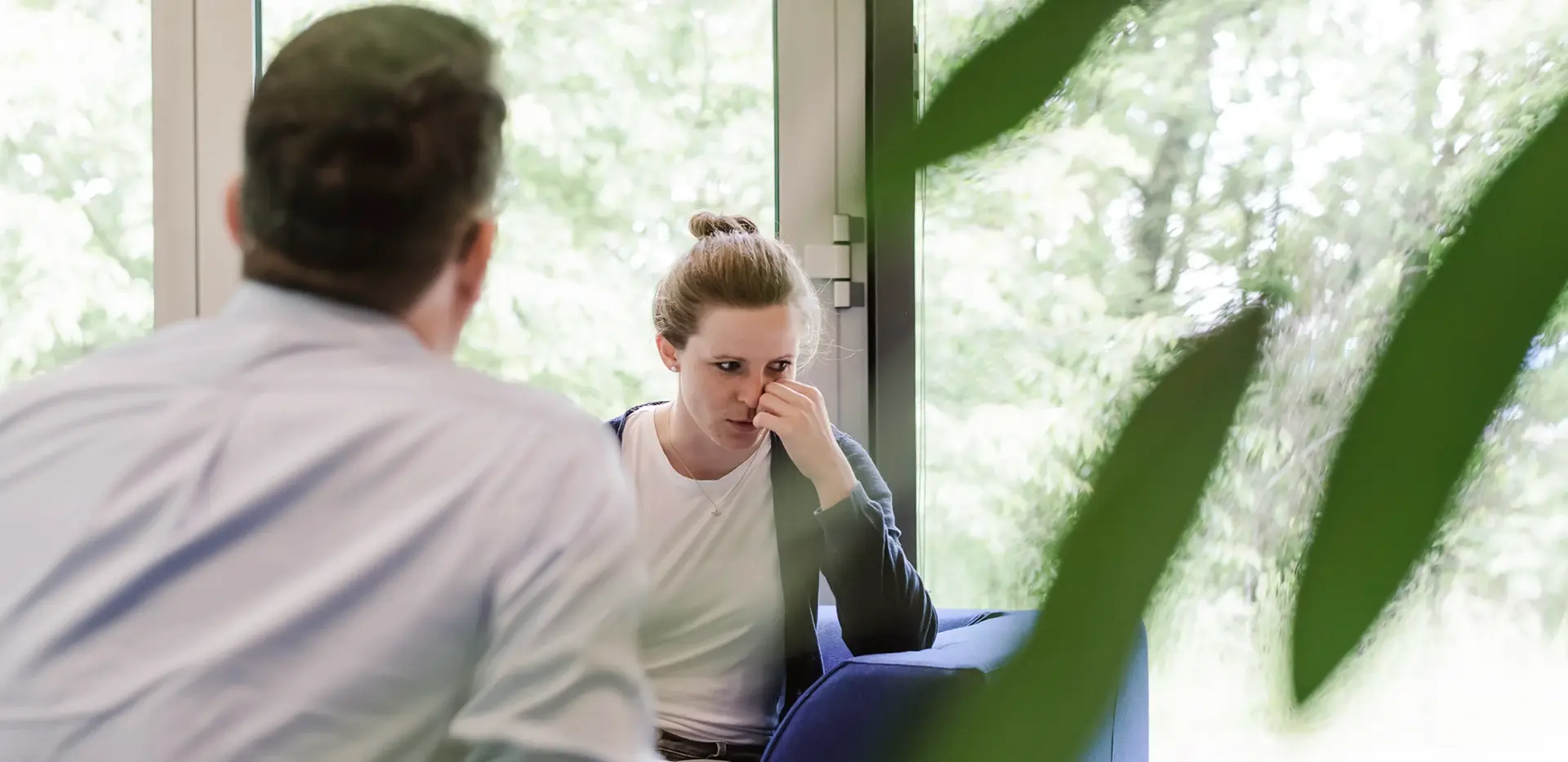 Ein Therapeut sitzt mit dem Rücken zur Kamera. Er ist in einem Gespräch mit einer Patientin.