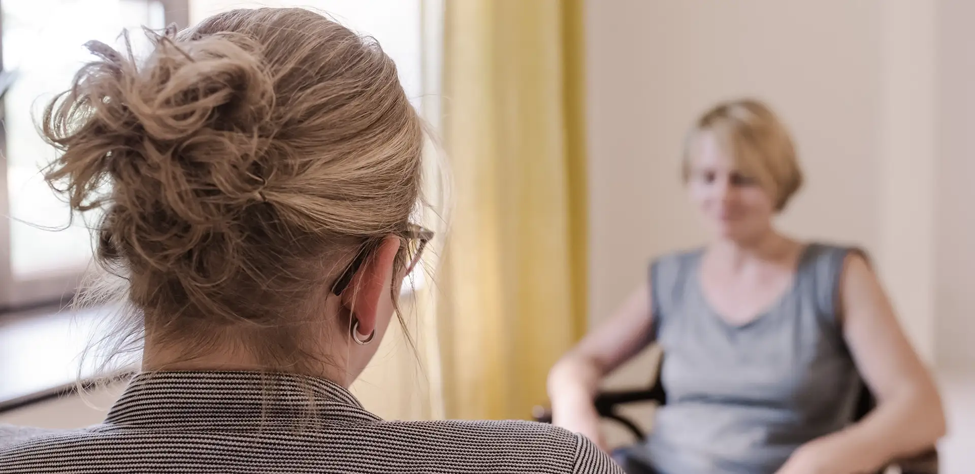 Eine Therapeutin von hinten, die ihrer Patientin gegenübersitzt.