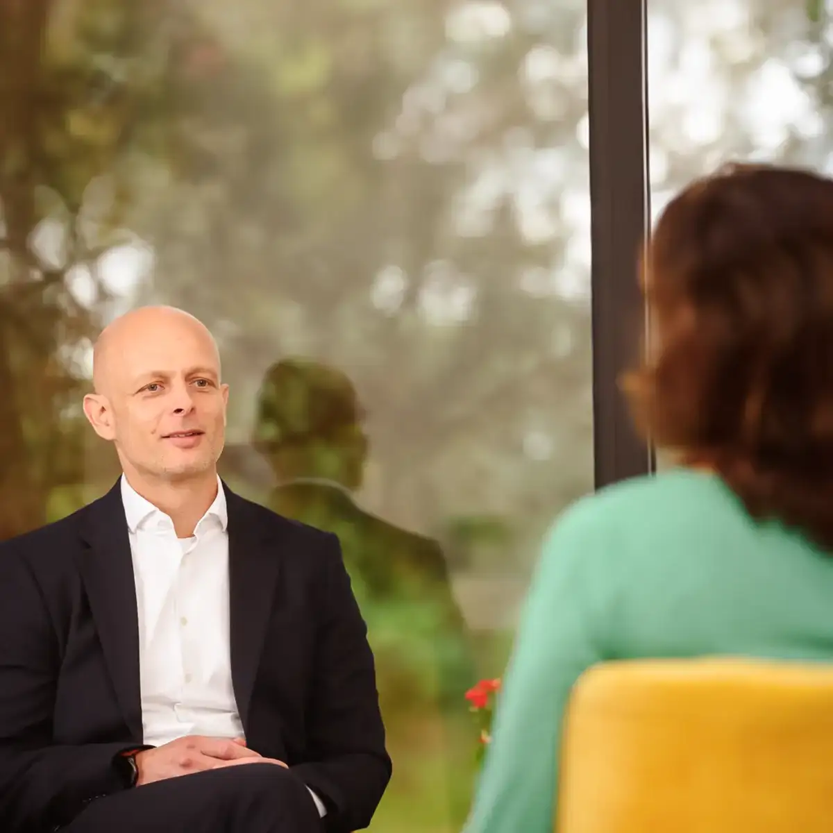 Ein Therapeut spricht mit seiner Patientin. Sie sitzen einander gegenüber.