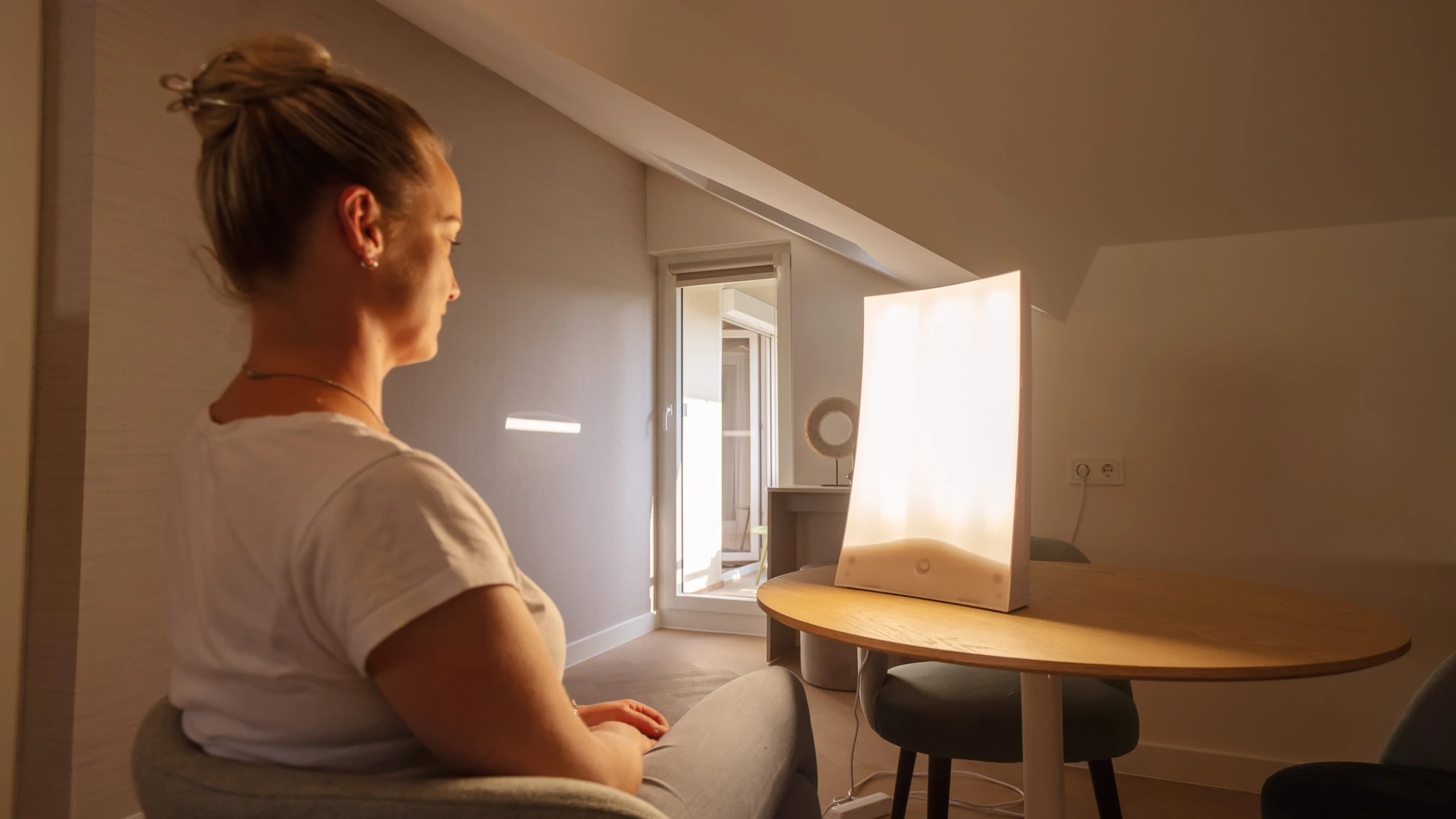 Eine schwarzweiß Aufnahme einer Frau, die am Fenster sitzt und hinausschaut.