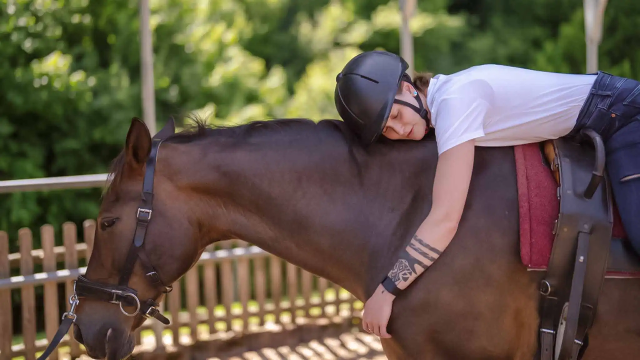 Eine Frau liegt entspannt auf dem Rücken eines Pferdes.