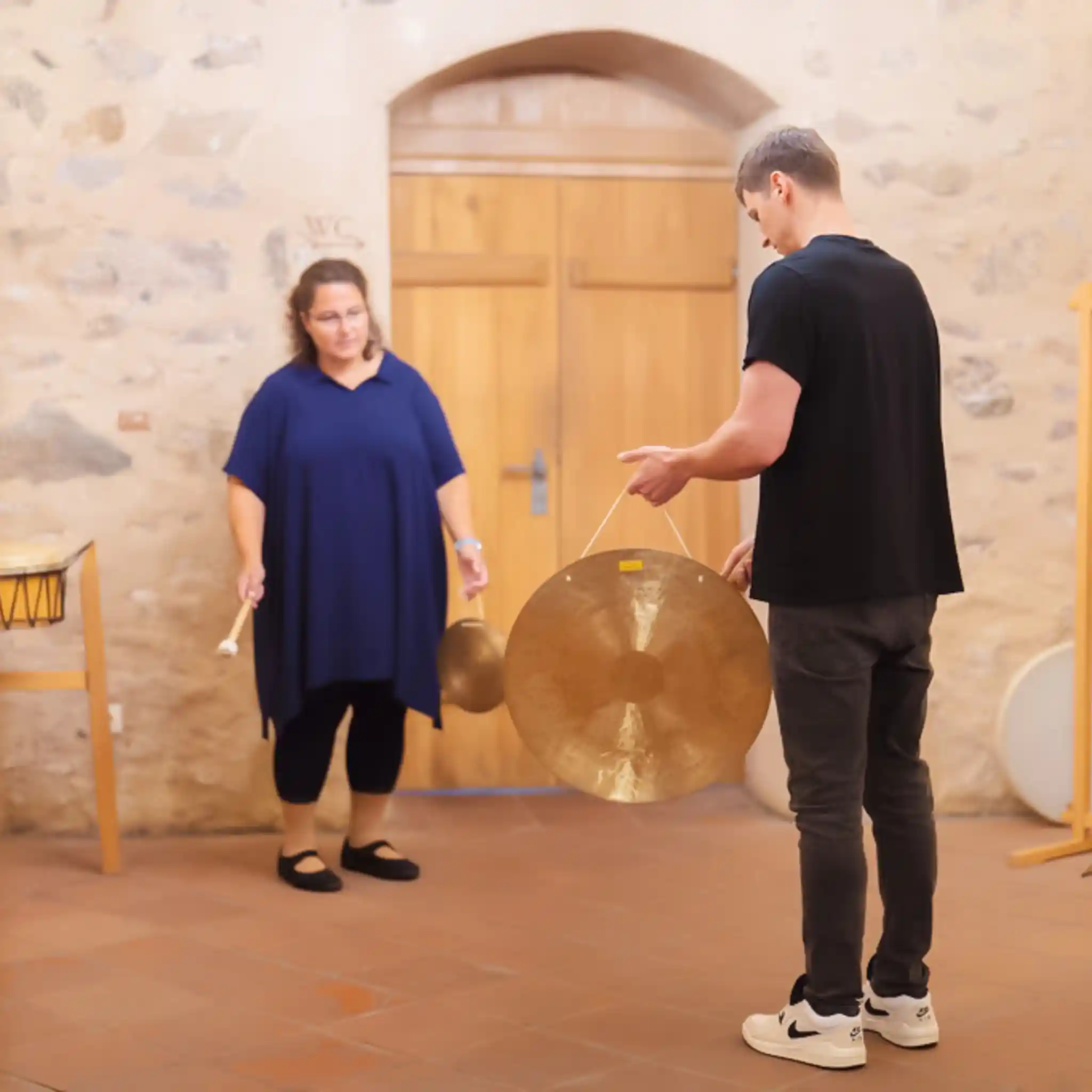 Ein Patient spielt einen Gong und spricht mit seinem Gegenüber.