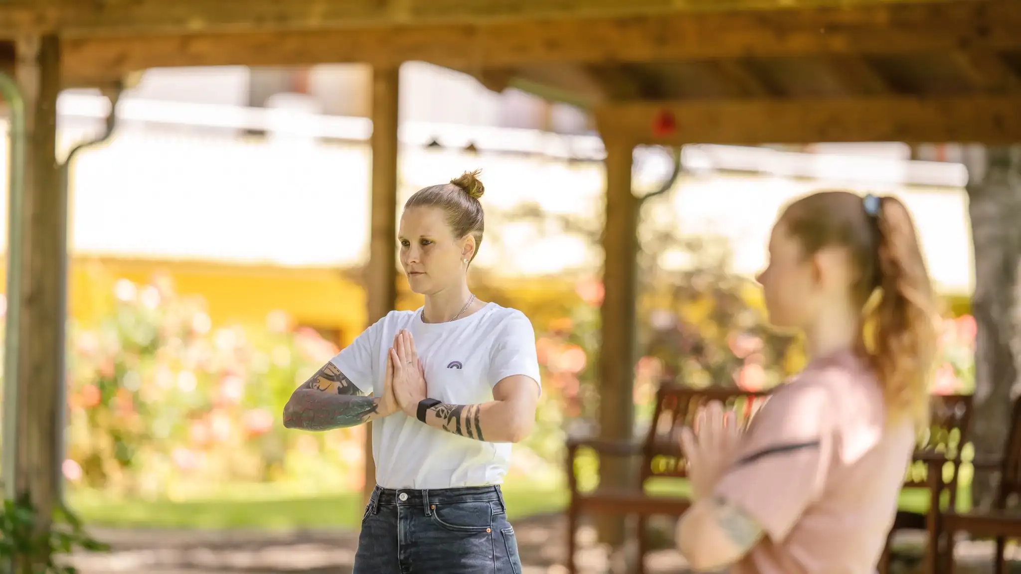 Zwei Frauen haben ihre Hände vor sich selbst aneinandergelegt in einer Yoga-Position.