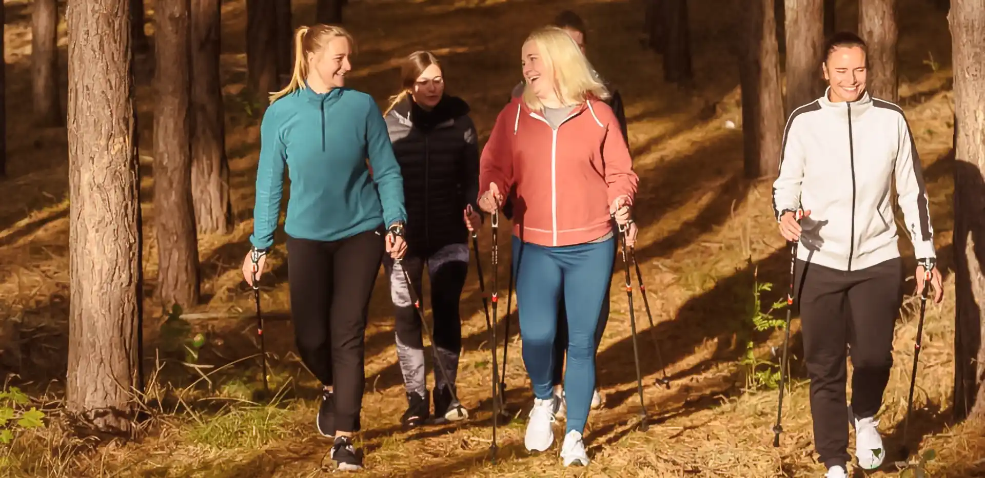 Mehrere Patientinnen machen im Wald gemeinsam Nordic Walking.
