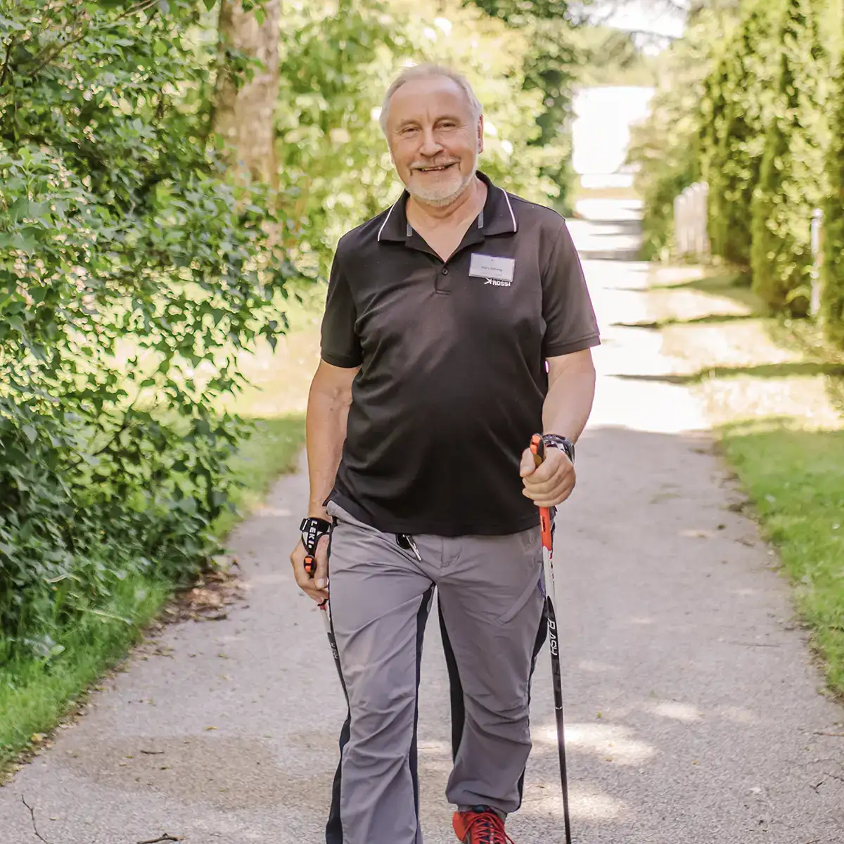Ein Mann läuft auf die Kamera zu mit Nordic Walking Stöcken in den Händen.