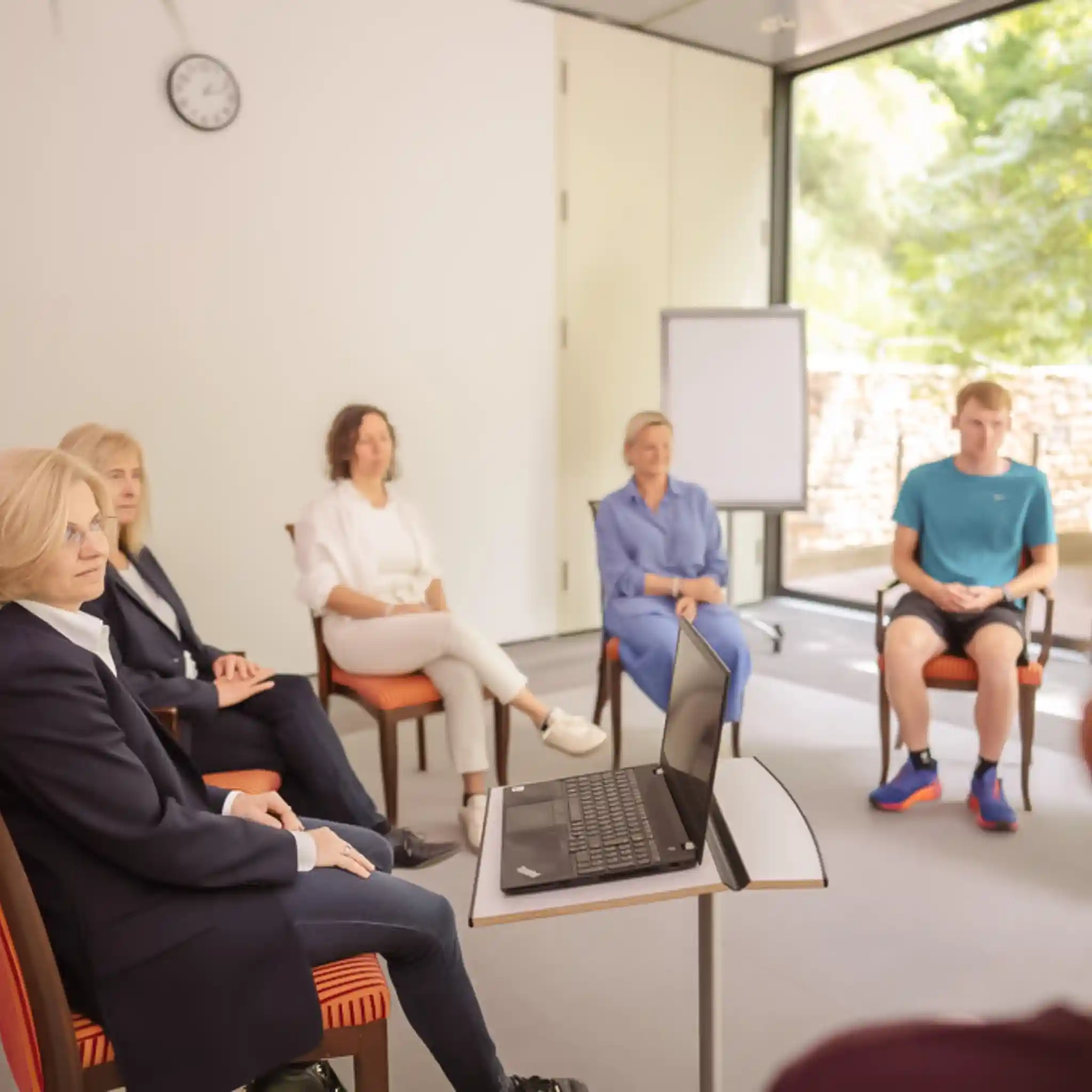 Eine Ärztin leitet eine Gruppentherapie mit einer Gruppe Patienten.