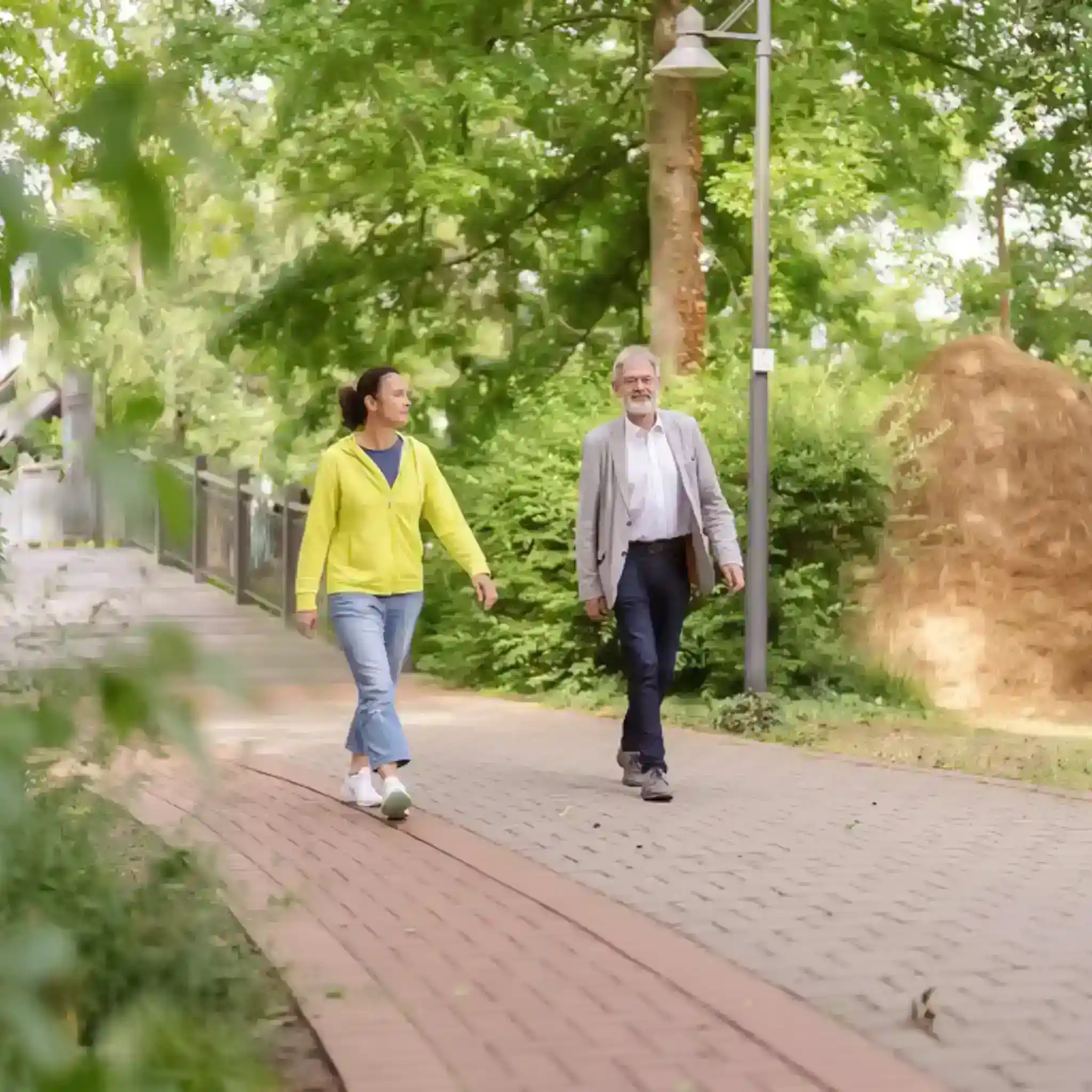 Ein Mann und eine Frauen gehen nebeneinander durch einen Park und unterhalten sich 