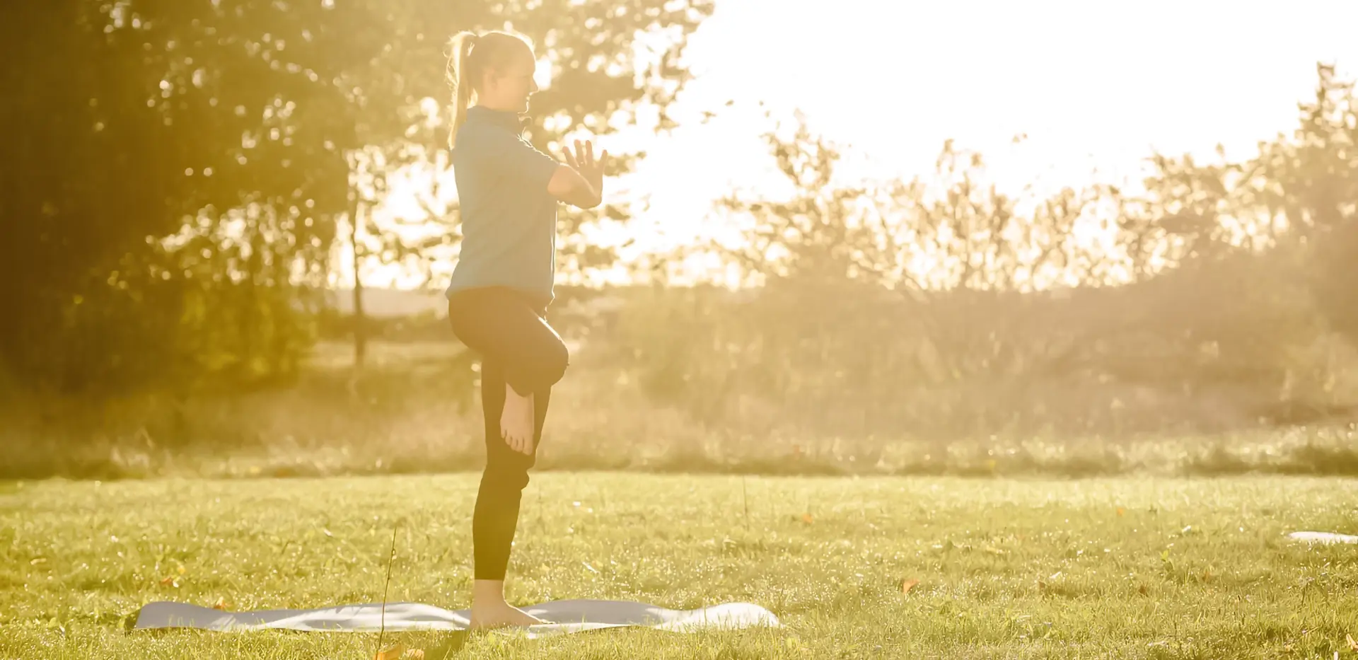 Eine Frau macht Yoga auf einer Wiese.