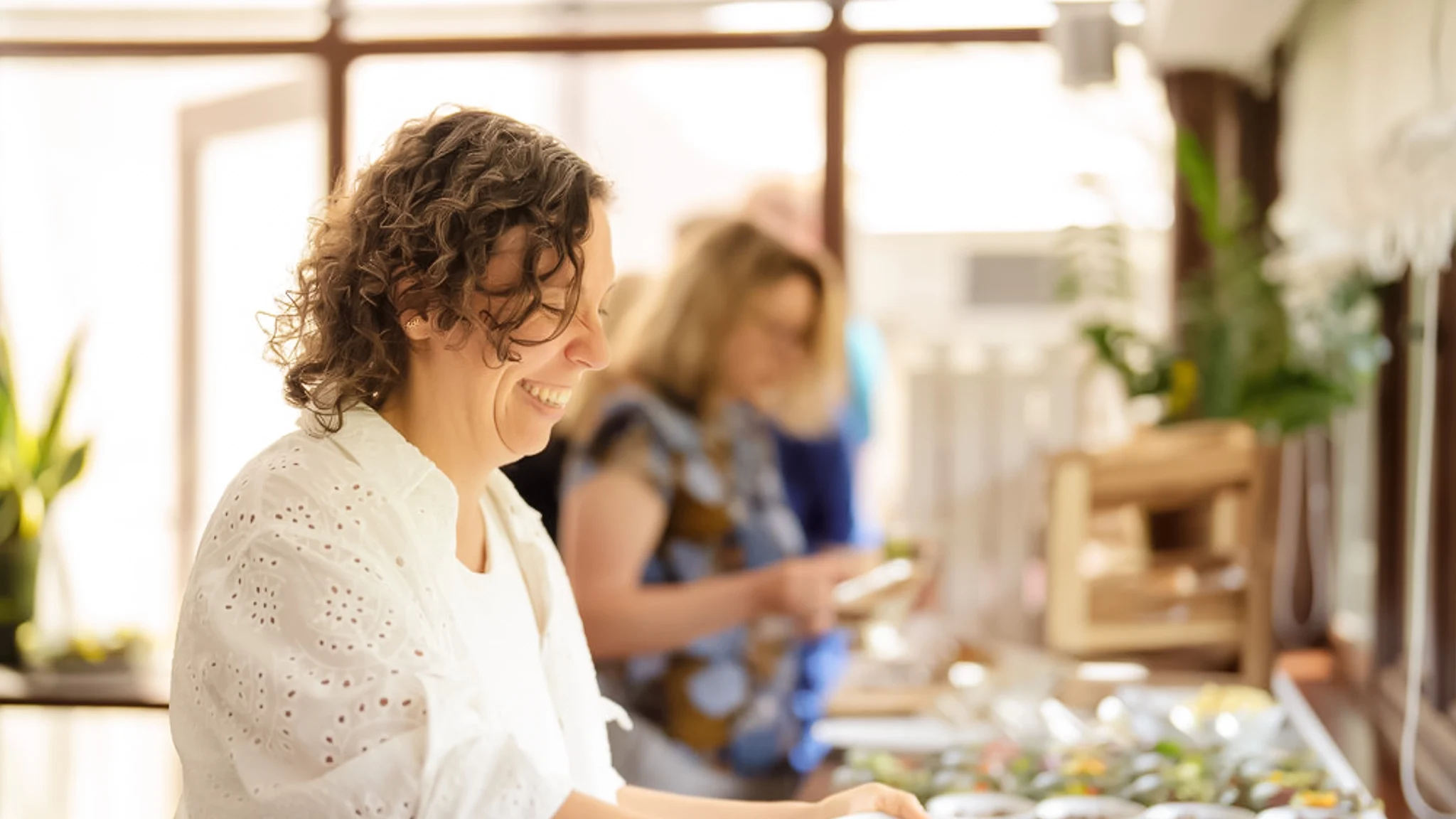 Eine Frau bedient sich am Buffet. Sie lacht.