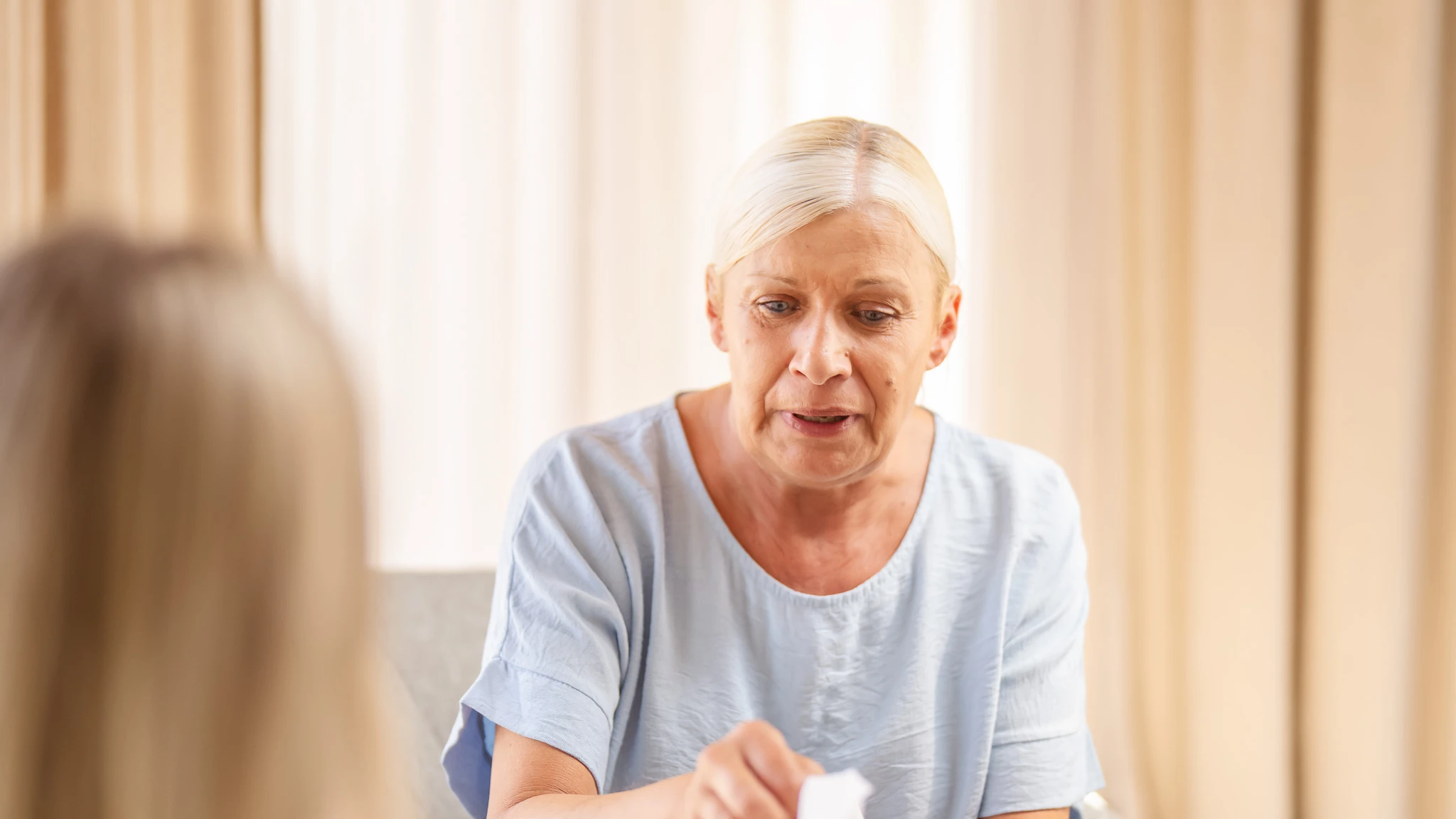 Nahaufnahme einer Patientin, die nach einem Taschentuch greift.
