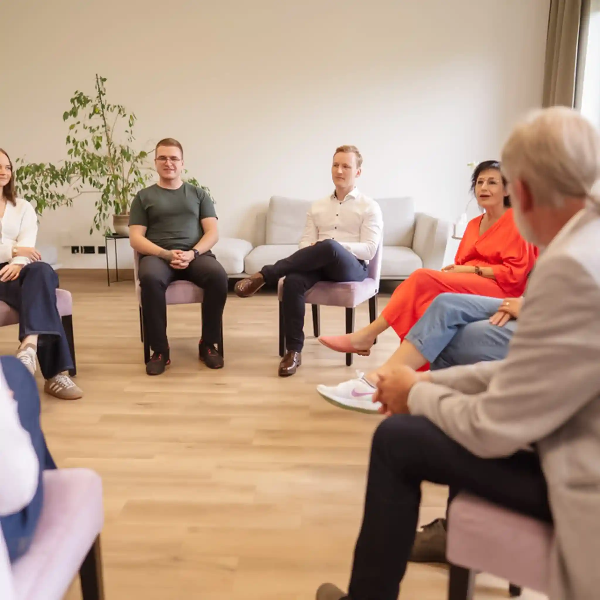 Mehrere Menschen sitzen zur Gruppen Therapie im Stuhlkreis