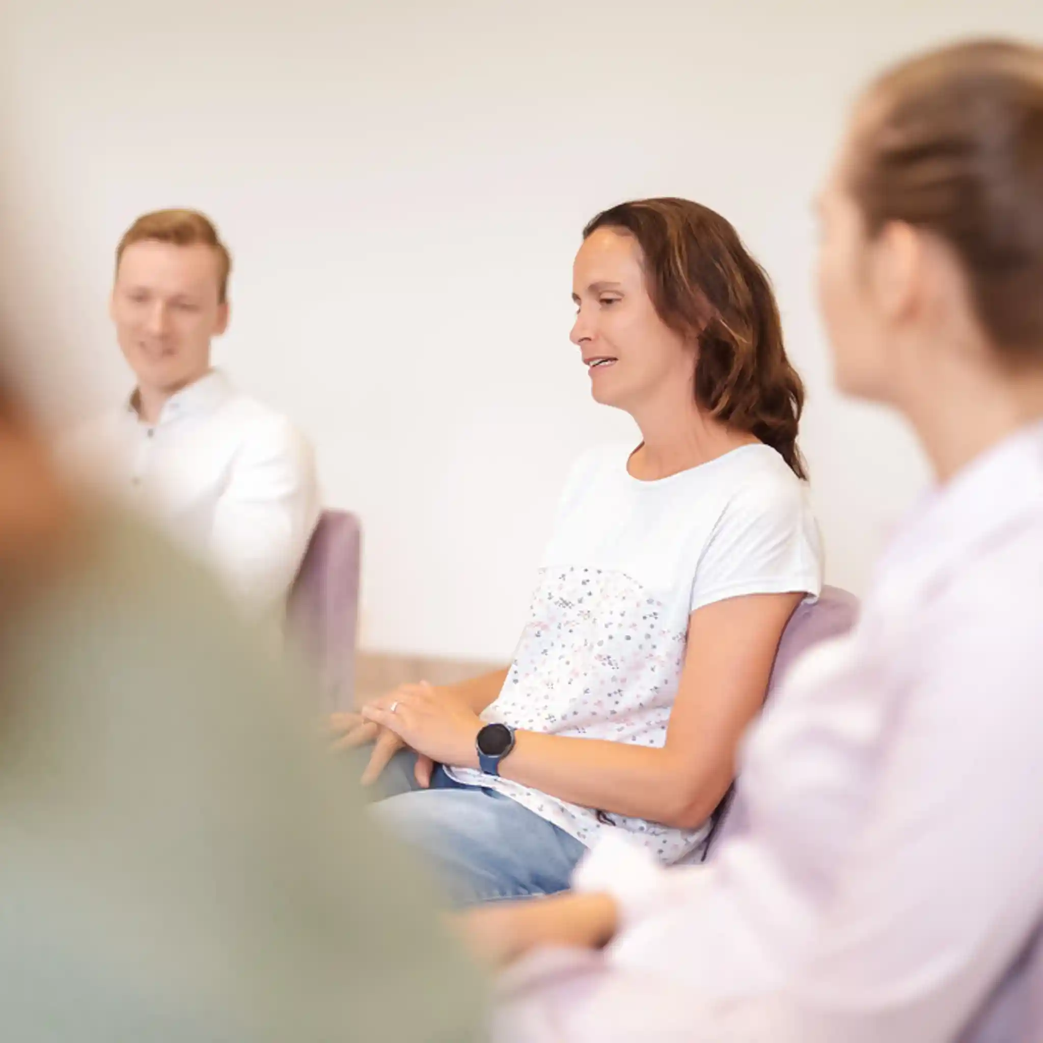 Eine Frau sitzt im Stuhlkreis bei einer Gruppen Therapie.