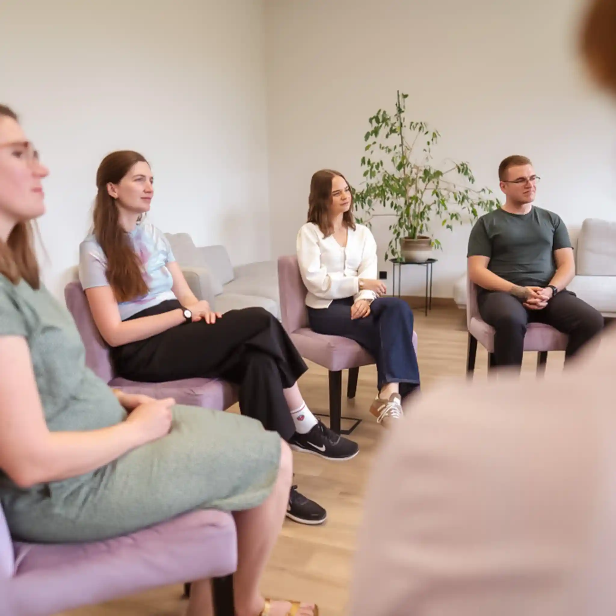 Mehrere Menschen sitzen bei einer Gruppen Therapie im Stuhlkreis