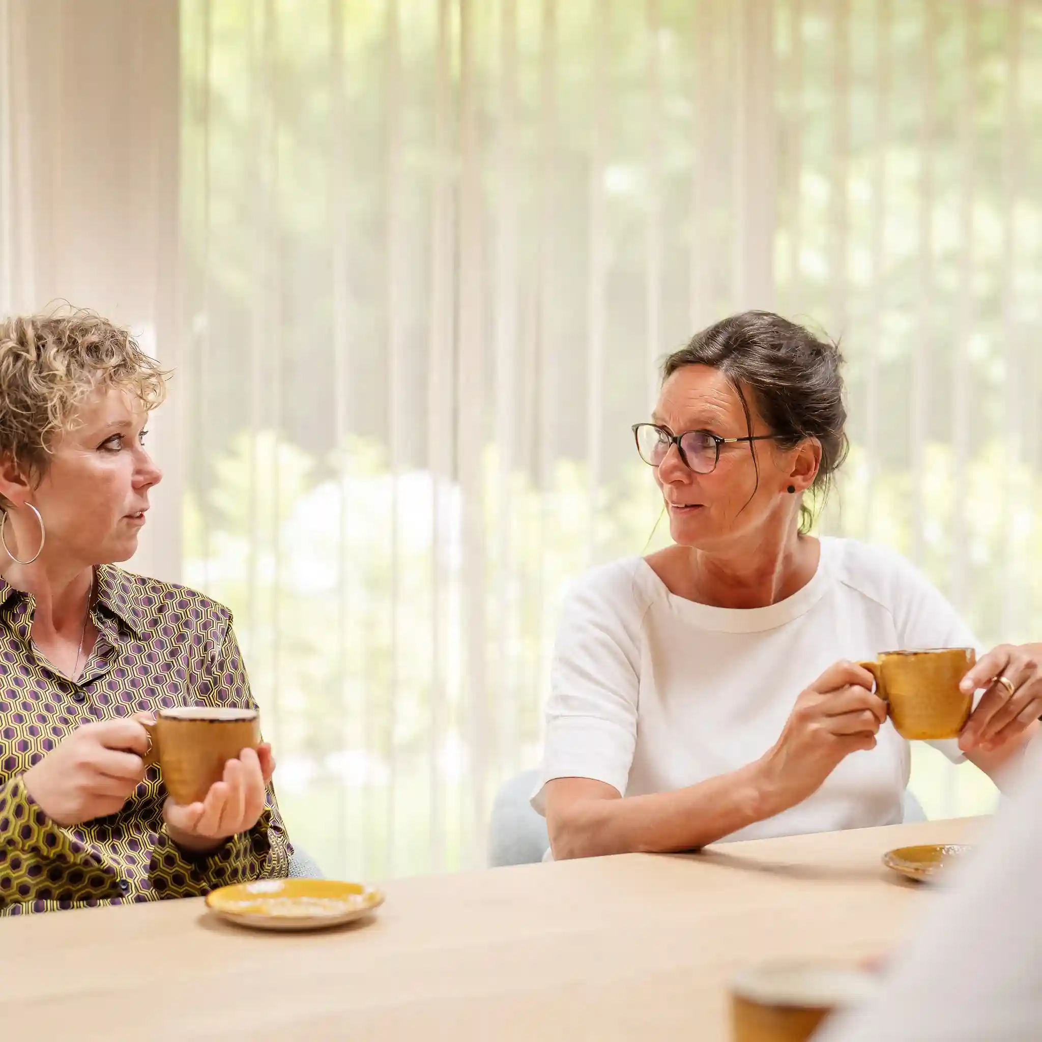 Zwei Frauen unterhalten sich und haben dabei eine Teetasse in der Hand