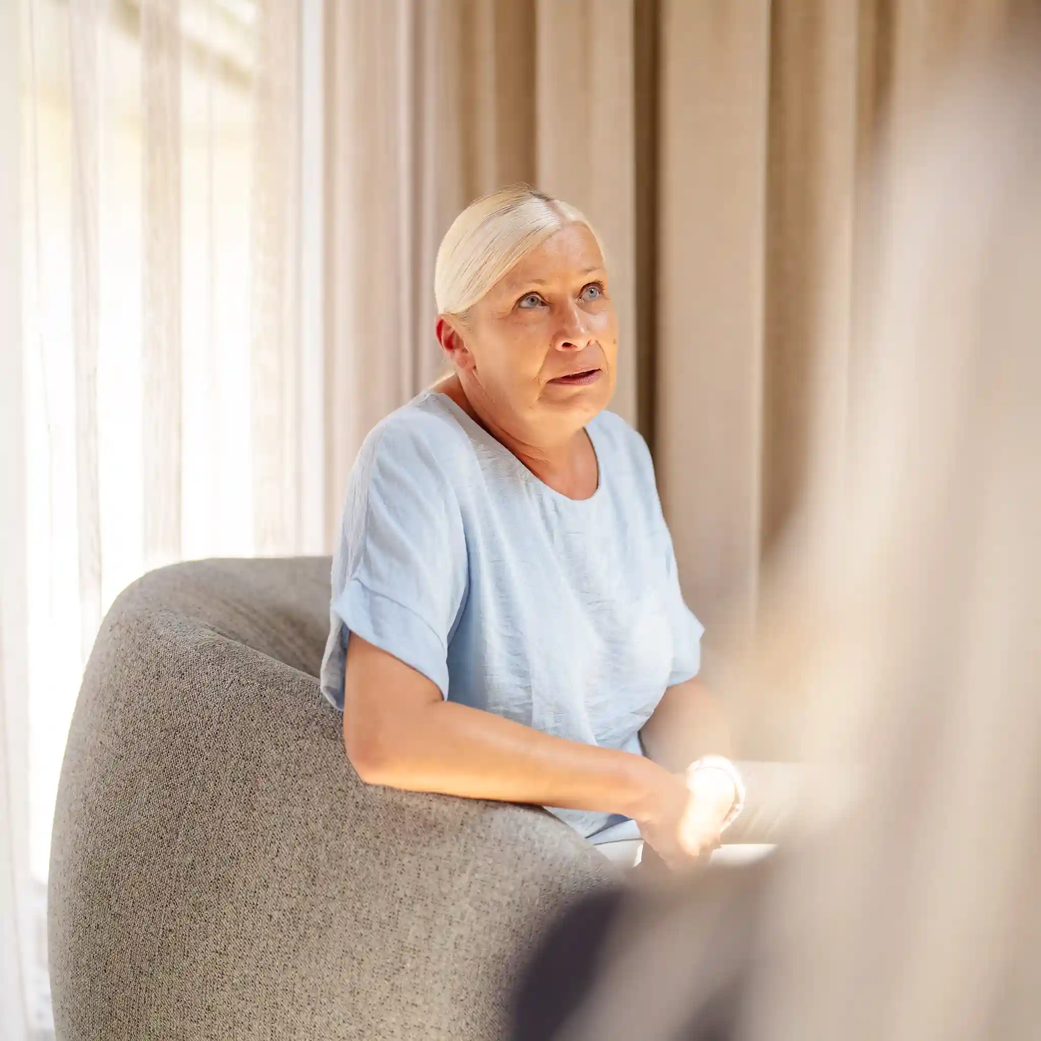Eine Frau in blauem T-shirt sitzt in einem Sessel.