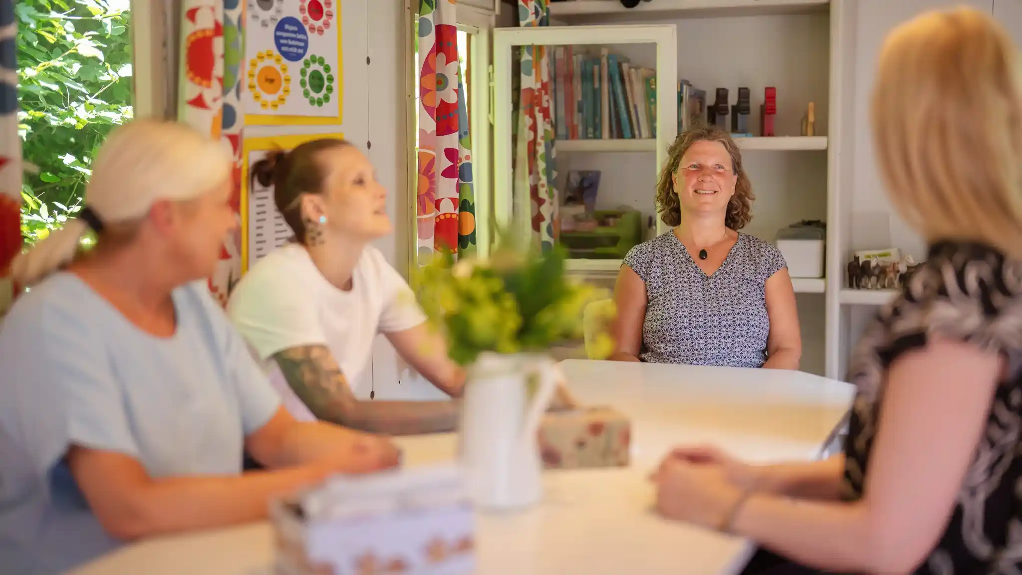 Mehrere Patientinnen sitzen bei einer Gruppentherapie gemeinsam am Tisch.