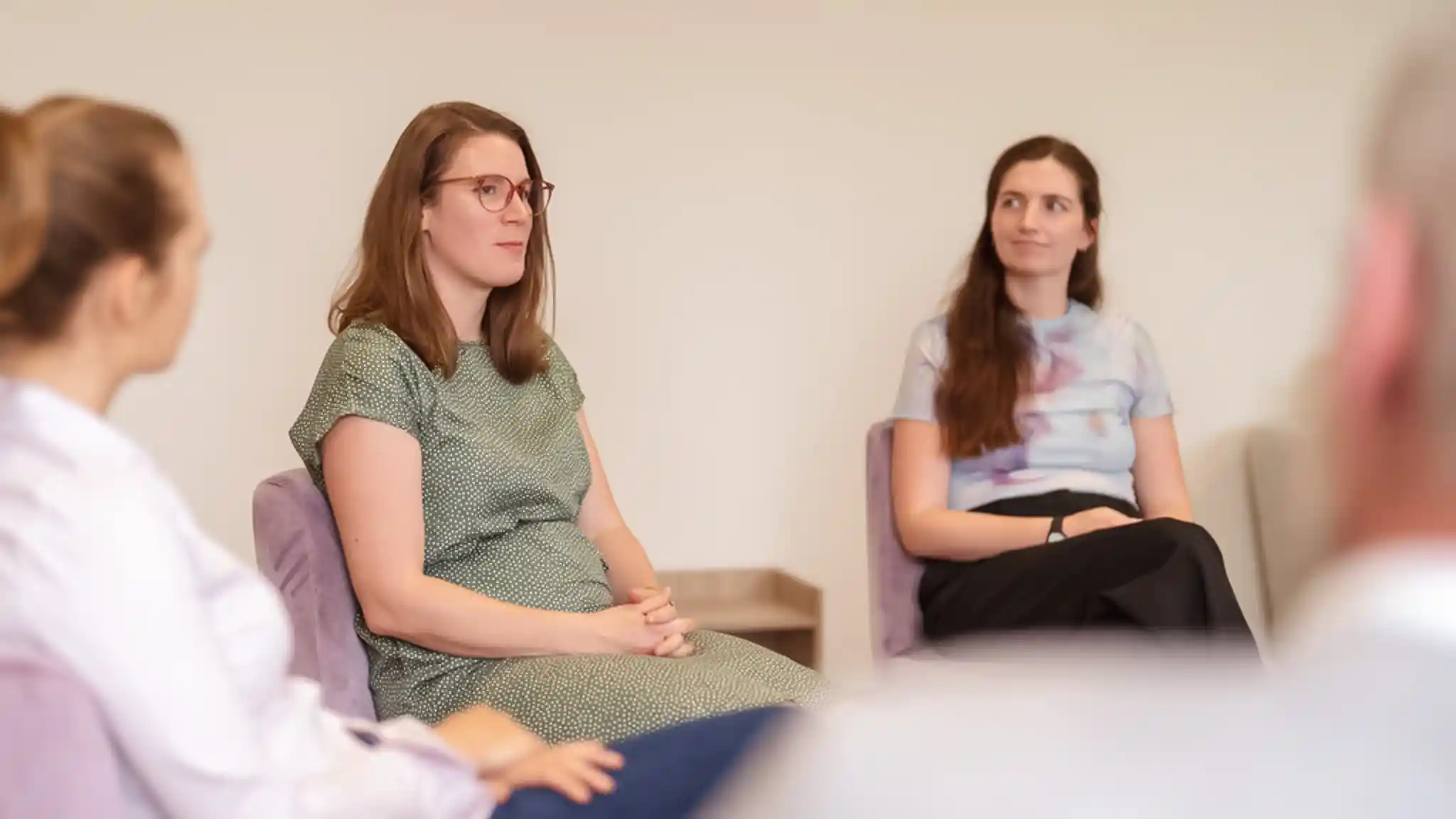 Mehrere Patienten sitzen auf Stühlen im Kreis bei einer Gruppentherapie.