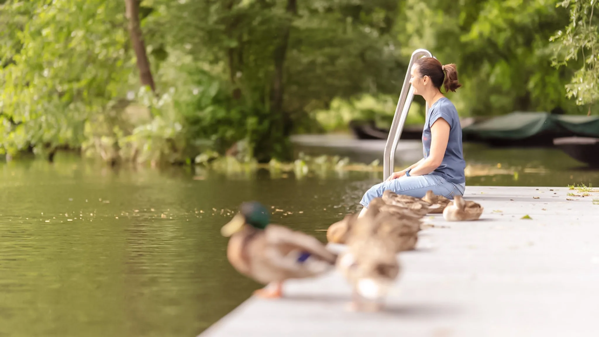 Eine Patientin sitzt am Ufer eines Sees im Wald.