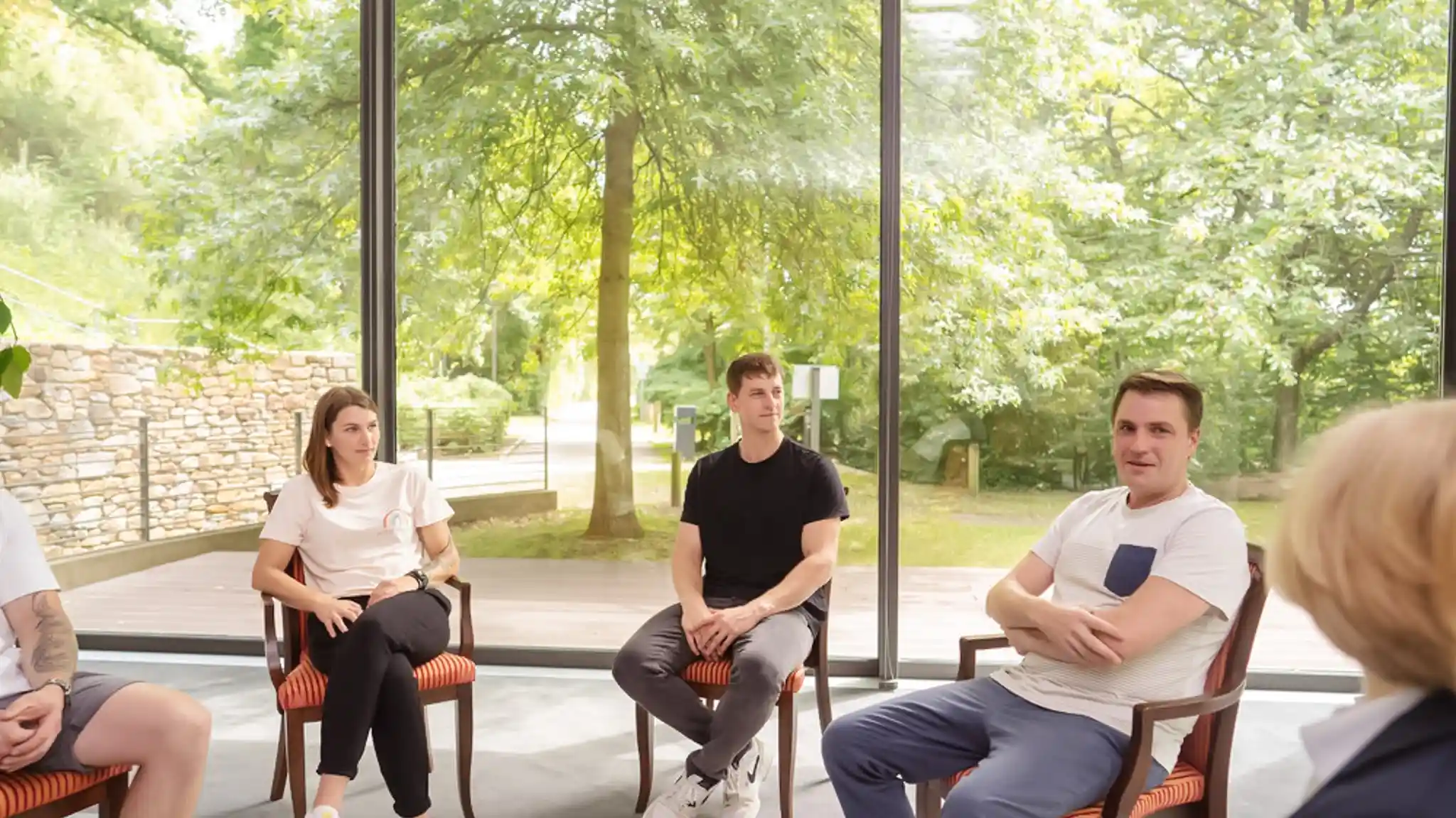 Mehrere Patienten sitzen in einem Stuhlkreis bei der Gruppentherapie