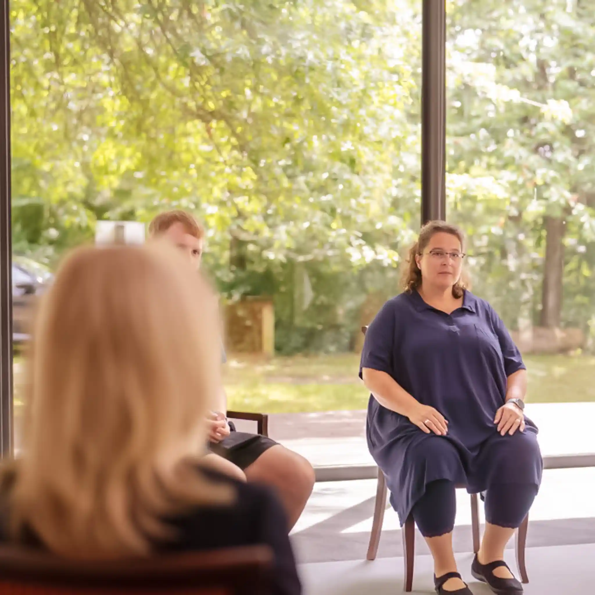 Eine Gruppentherapie mit mehreren Patienten, die in einem Stuhlkreis sitzen.