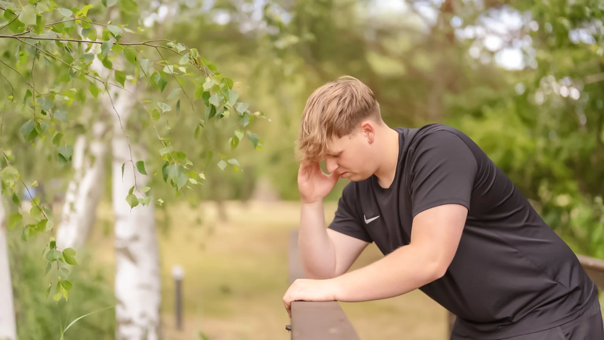 Ein Mann stützt seinen Kopf in seine Hand. Er lehnt an einem Geländer.