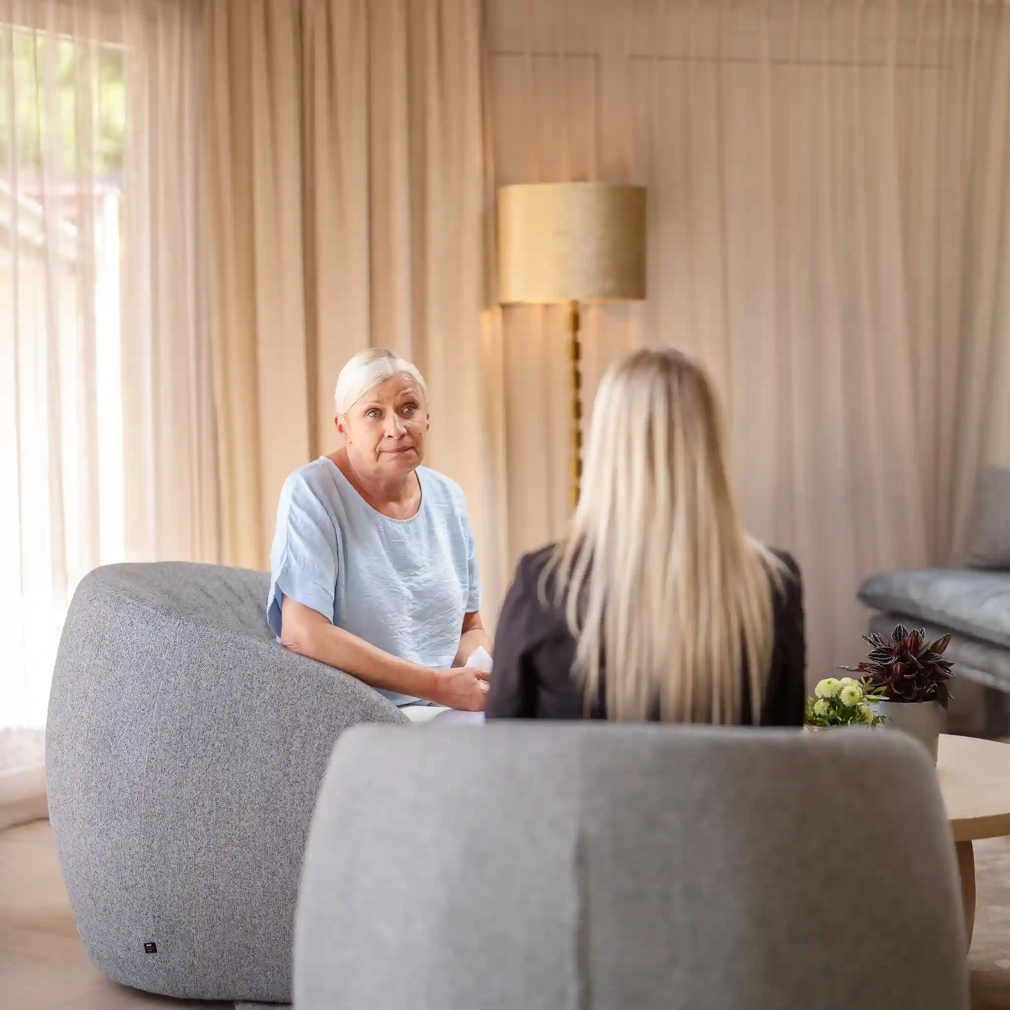 Eine Patientin sitzt ihrer Therapeutin gegenüber, beide sitzen in einem Sessel