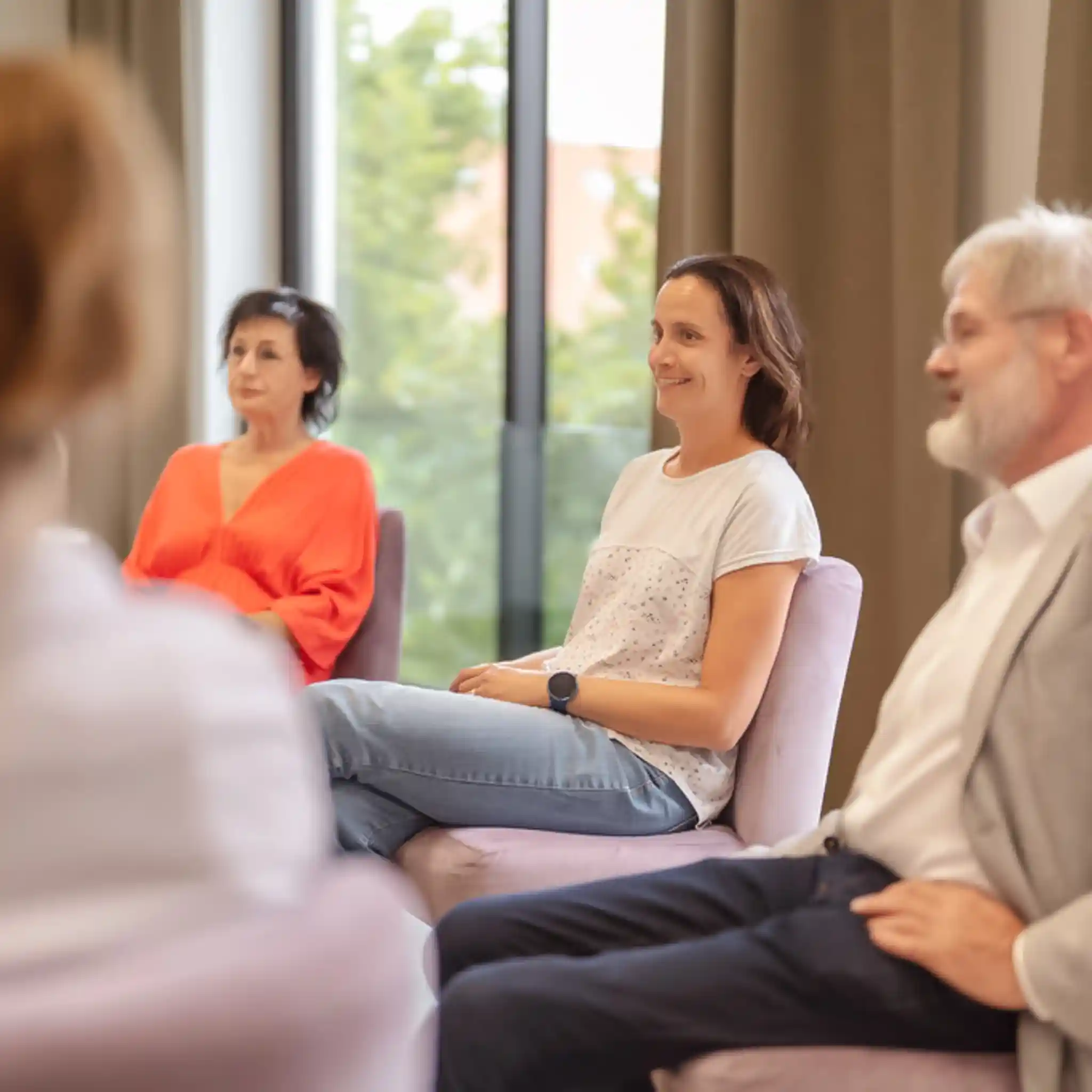 Mehrere Personen sitzen im Stuhlkreis bei einer Gruppentherapie