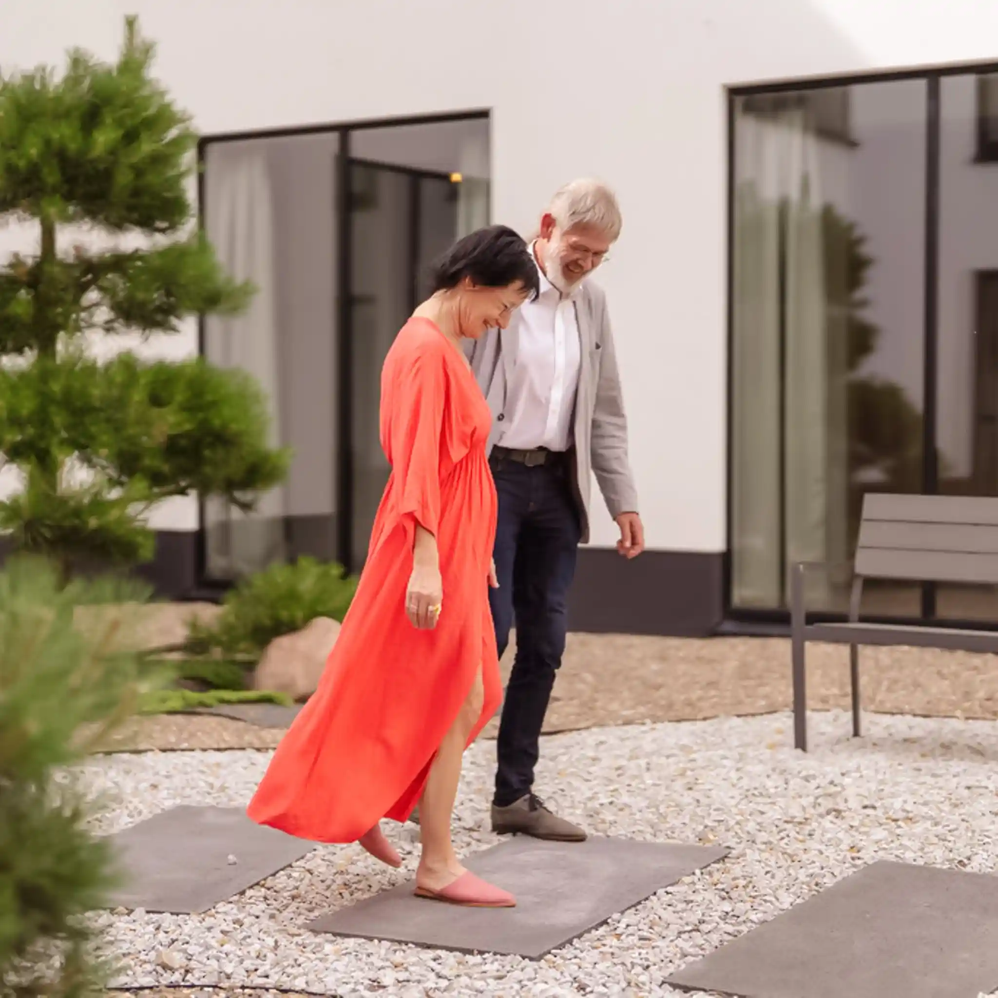 Ein Mann und eine Frau laufen vor einem Gebäude und unterhalten sich dabei