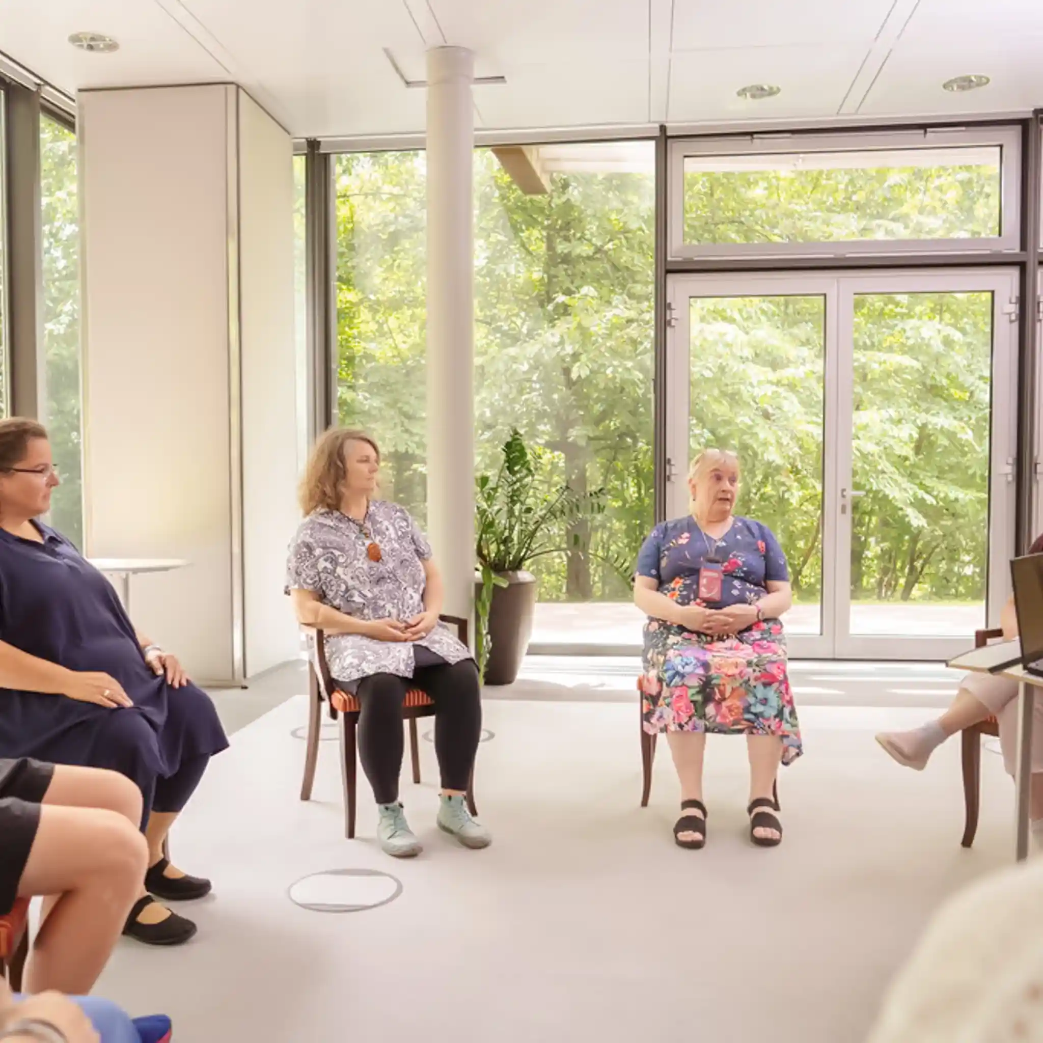 Mehrere Patienten sitzen im Stuhlkreis bei einer Gruppentherapie