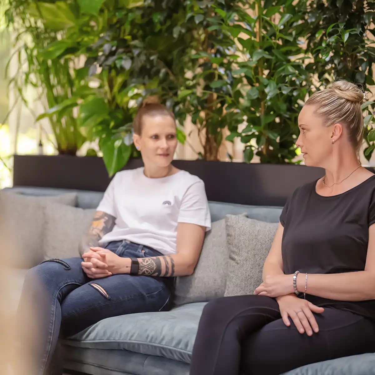 Zwei Frauen sitzen nebeneinander auf einem Sofa und Unterhalten sich