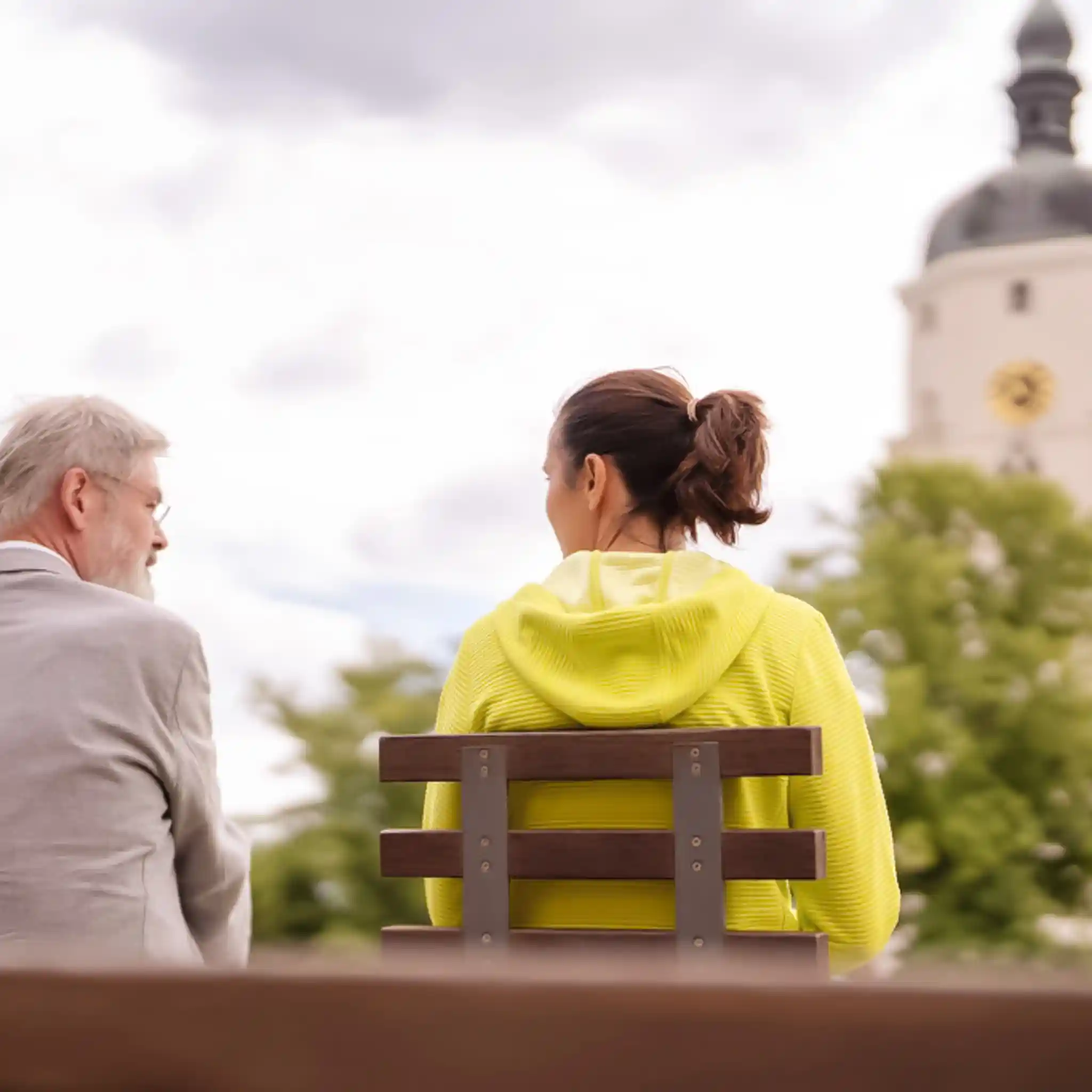 Ein Arzt und eine Borderline-Patientin sitzen mit dem Rücken zur Kamera auf einer Parkbank.