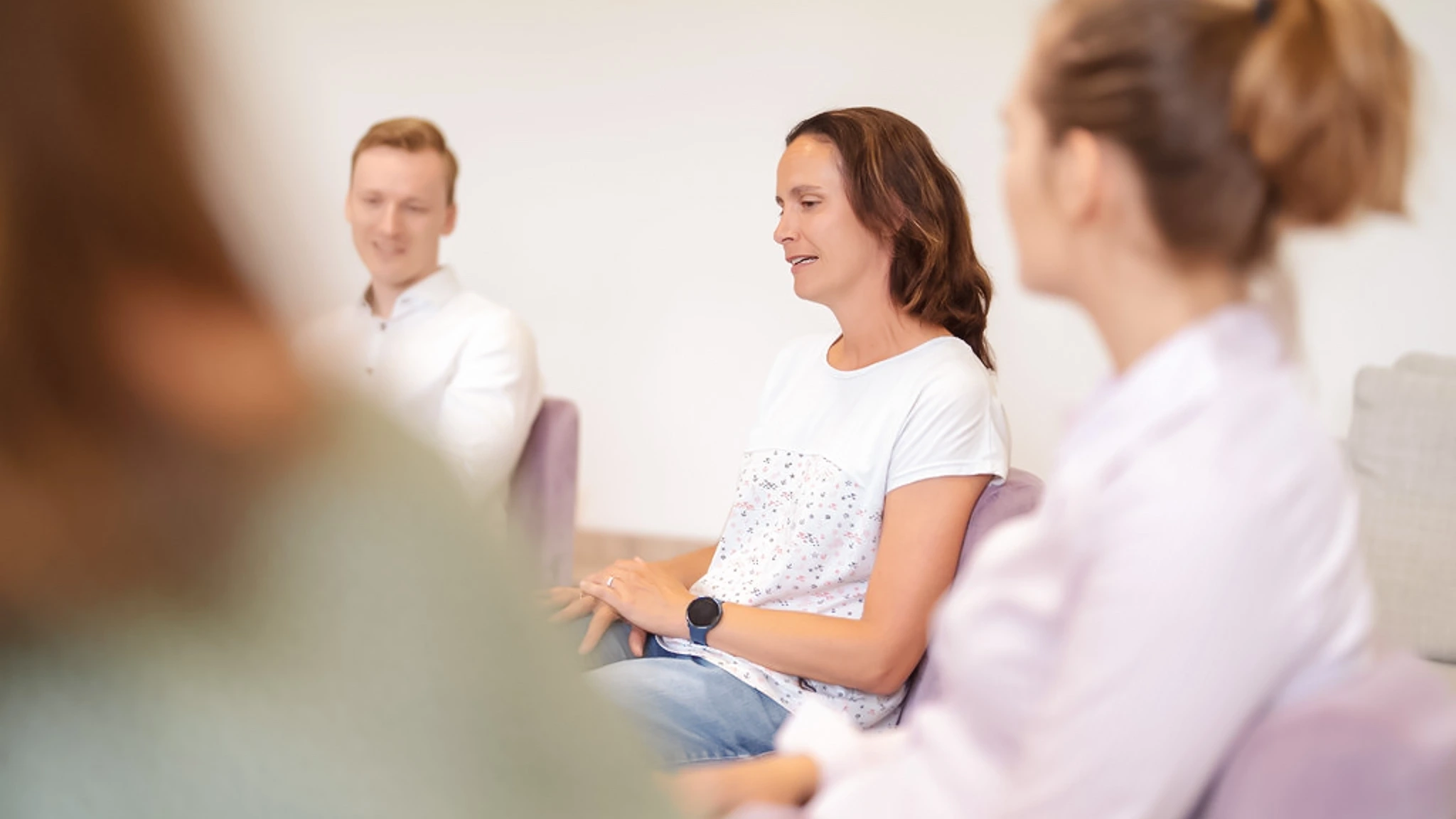Eine Patientin erzählt etwas in einer Gruppentherapie, die anderen hören ihr zu.