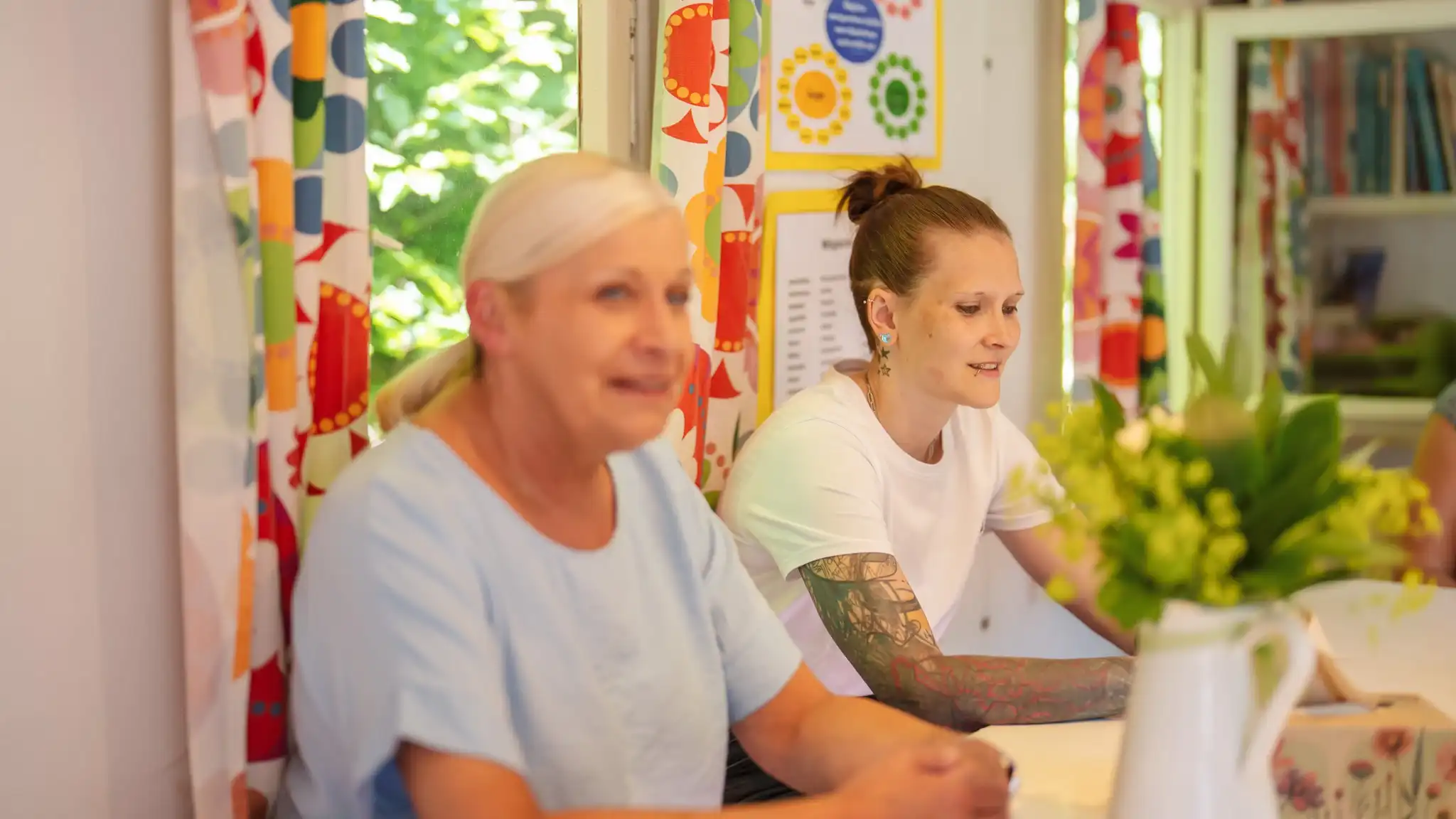 Zwei Patientinnen sitzen nebeneinander an einem Tisch.