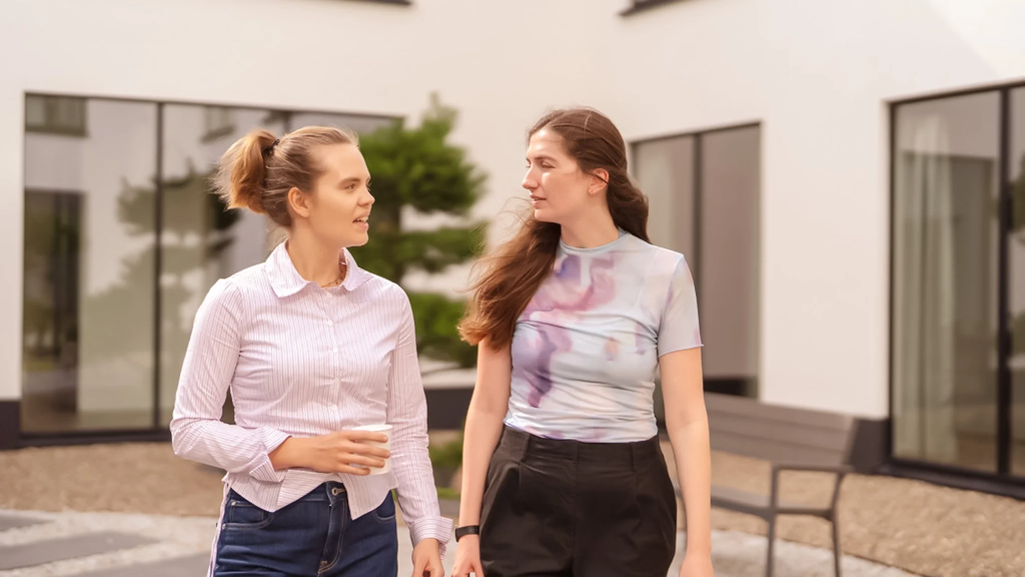 Zwei junge Frauen laufen gemeinsam durch einen Innenhof.
