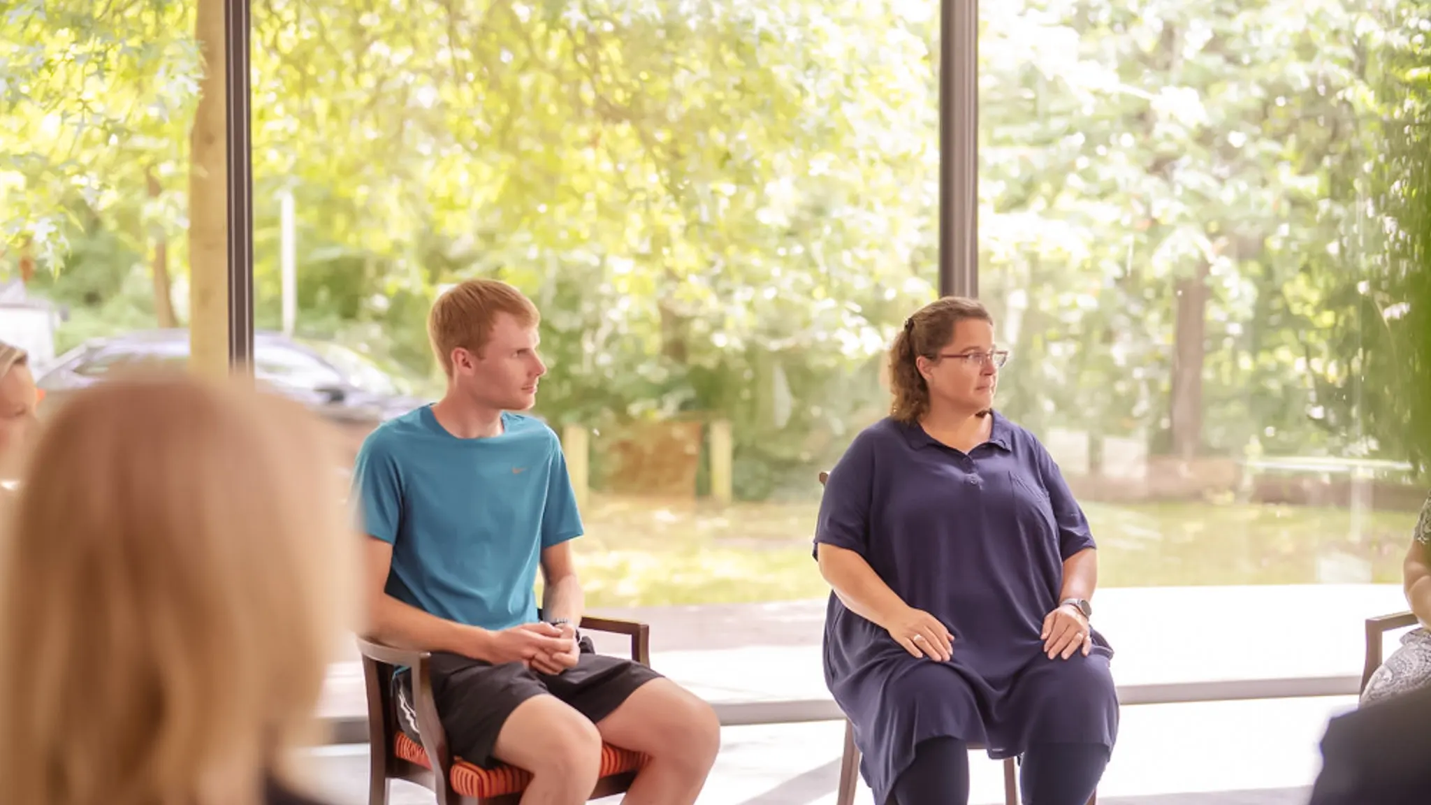 Mehrere Patienten sitzen in einem Stuhlkreis bei einer Gruppentherapie.