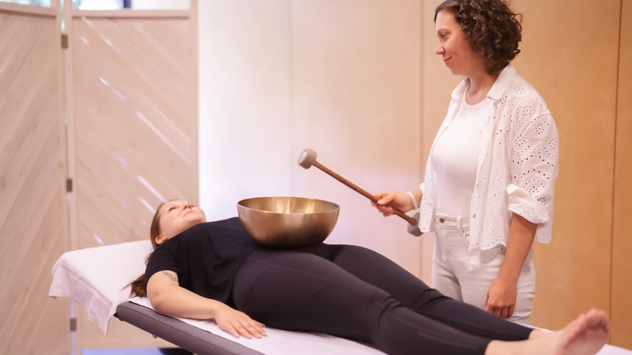 Eine Therapeutin führt eine Klangmassage bei einer Patientin durch.