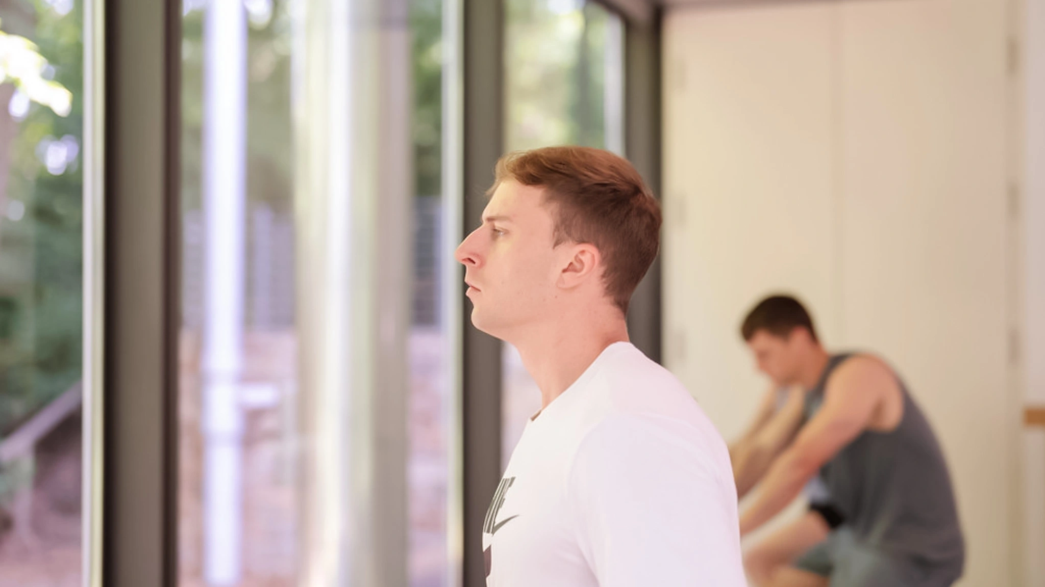 Ein Mann blickt aus dem Fenster in einem Fitnessstudio nach draußen.