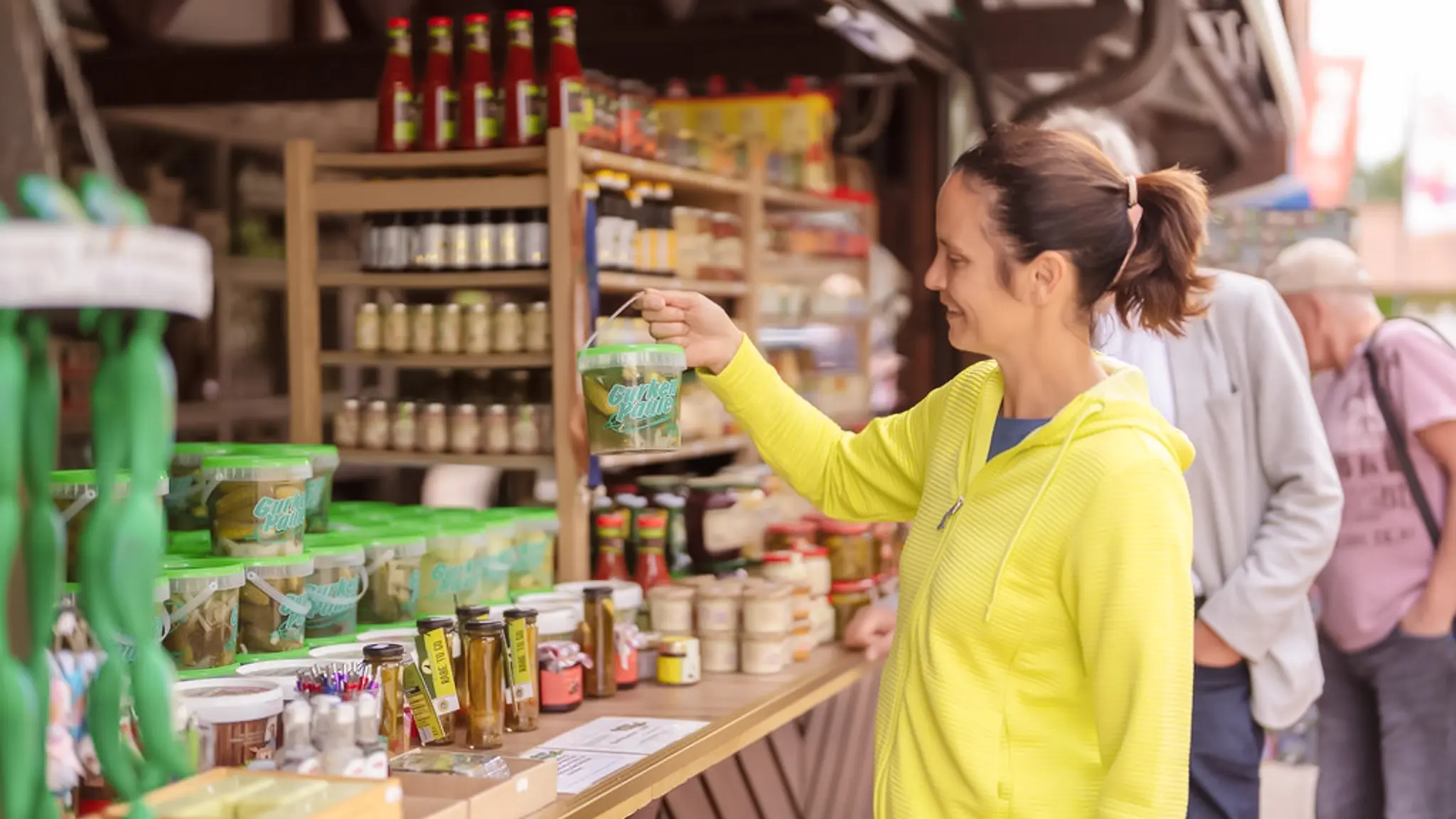 Eine Frau kauft eingelegte Gurken an einem Marktstand.