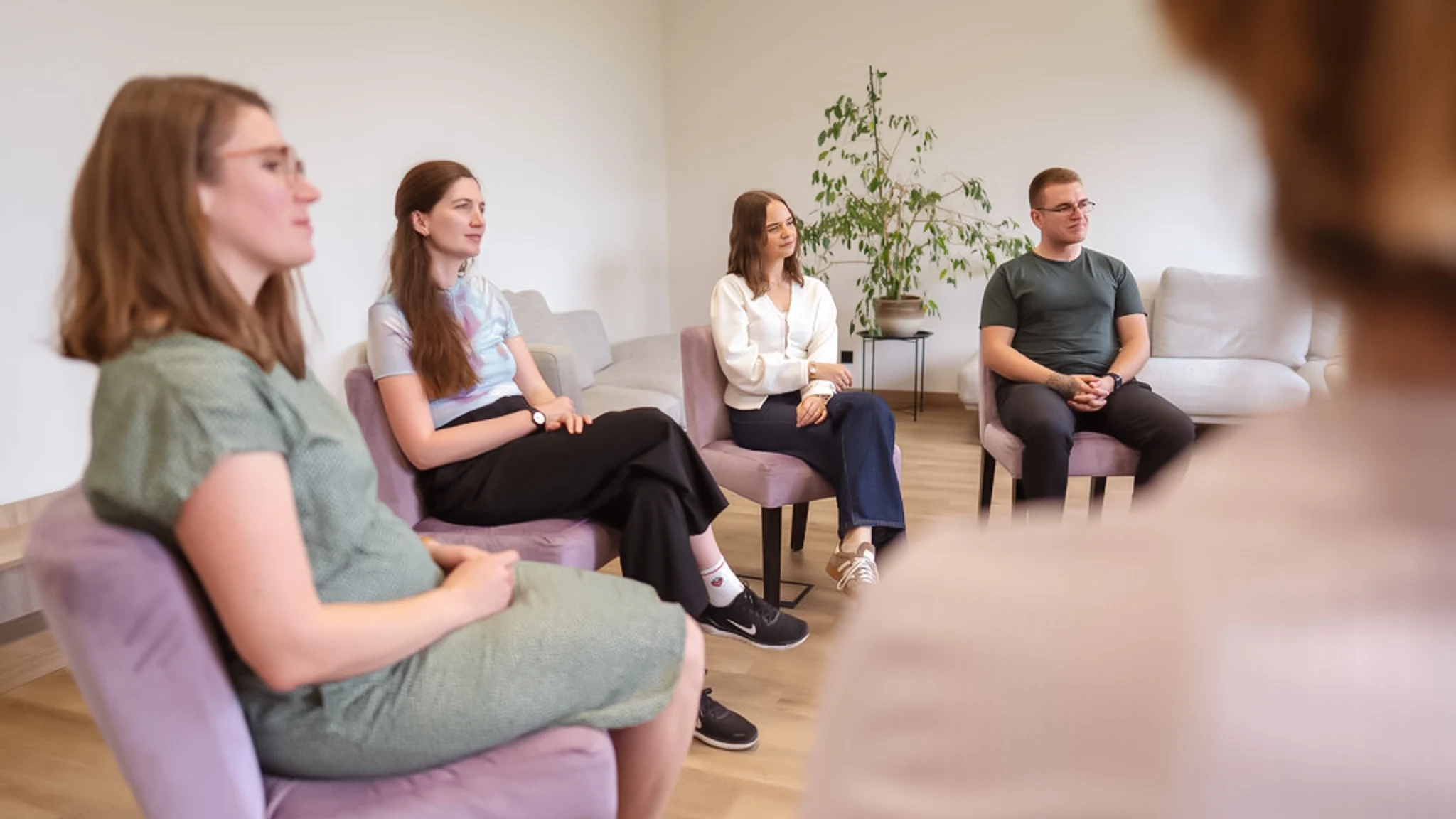 Mehrere Personen sitzen in einem Stuhlkreis bei einer Gruppentherapie