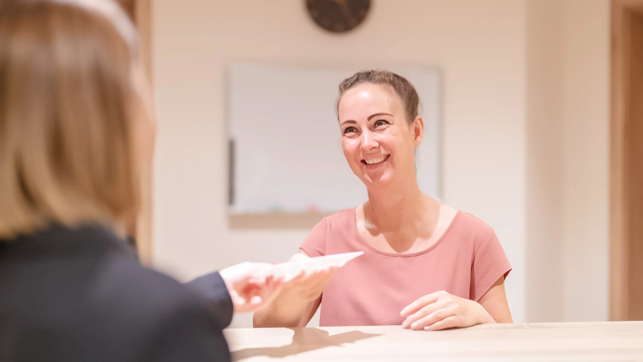 Eine Patientin bekommt Unterlagen von einer Patientenmanagerin überreicht.