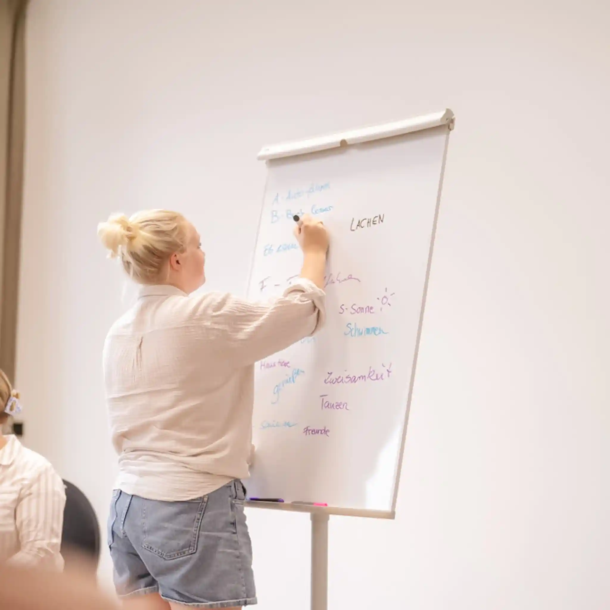 Eine Lehrerin schreibt etwas auf ein Whiteboard.