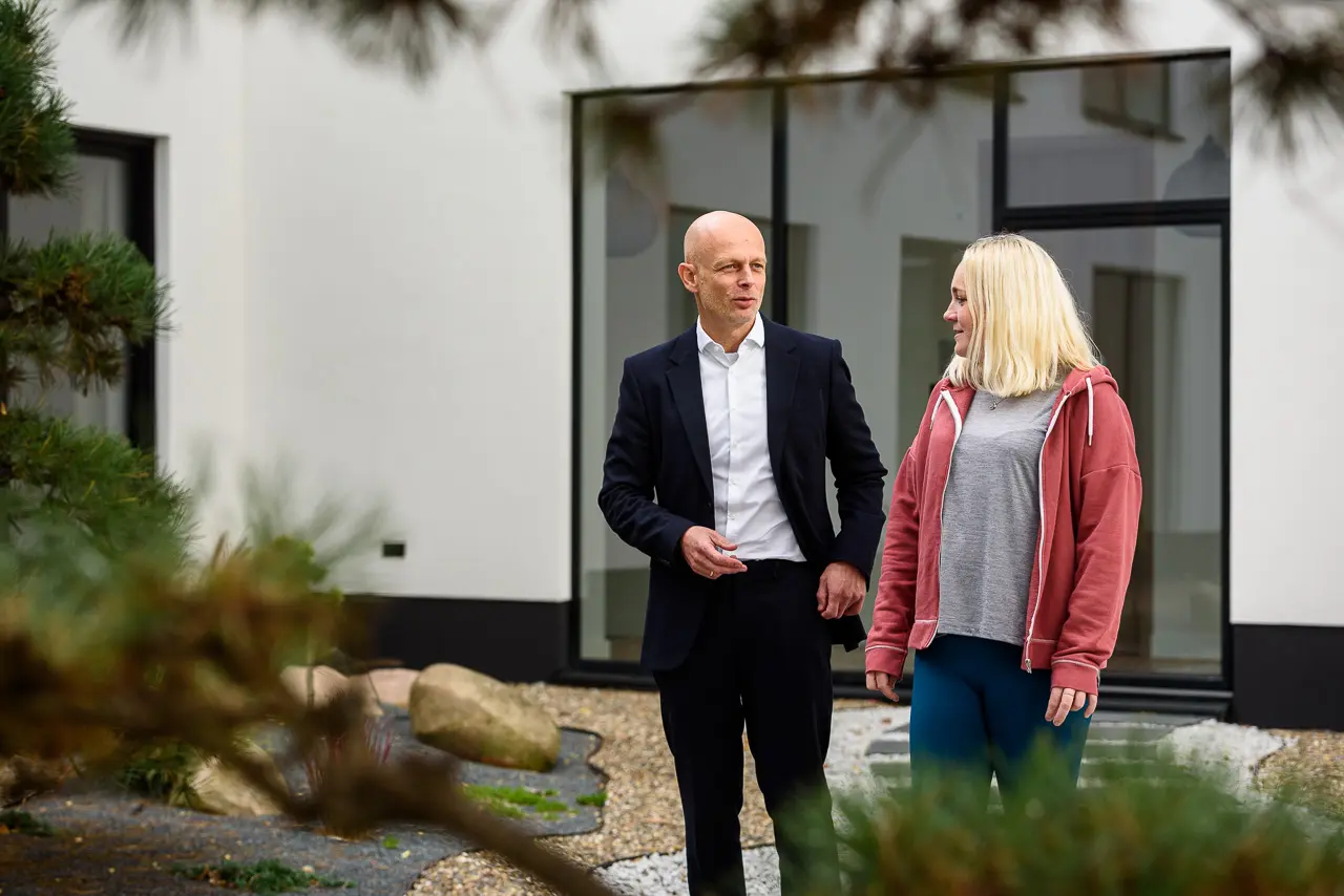 Eine Frau mit Winterdepression geht neben dem Psychotherapeuten Sascha Fischer durch den Innenhof einer Vincera Klinik.