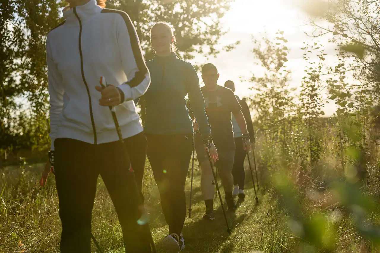 Mehrere Patienten laufen mit Laufstöcken gemeinsam durch den Wald.