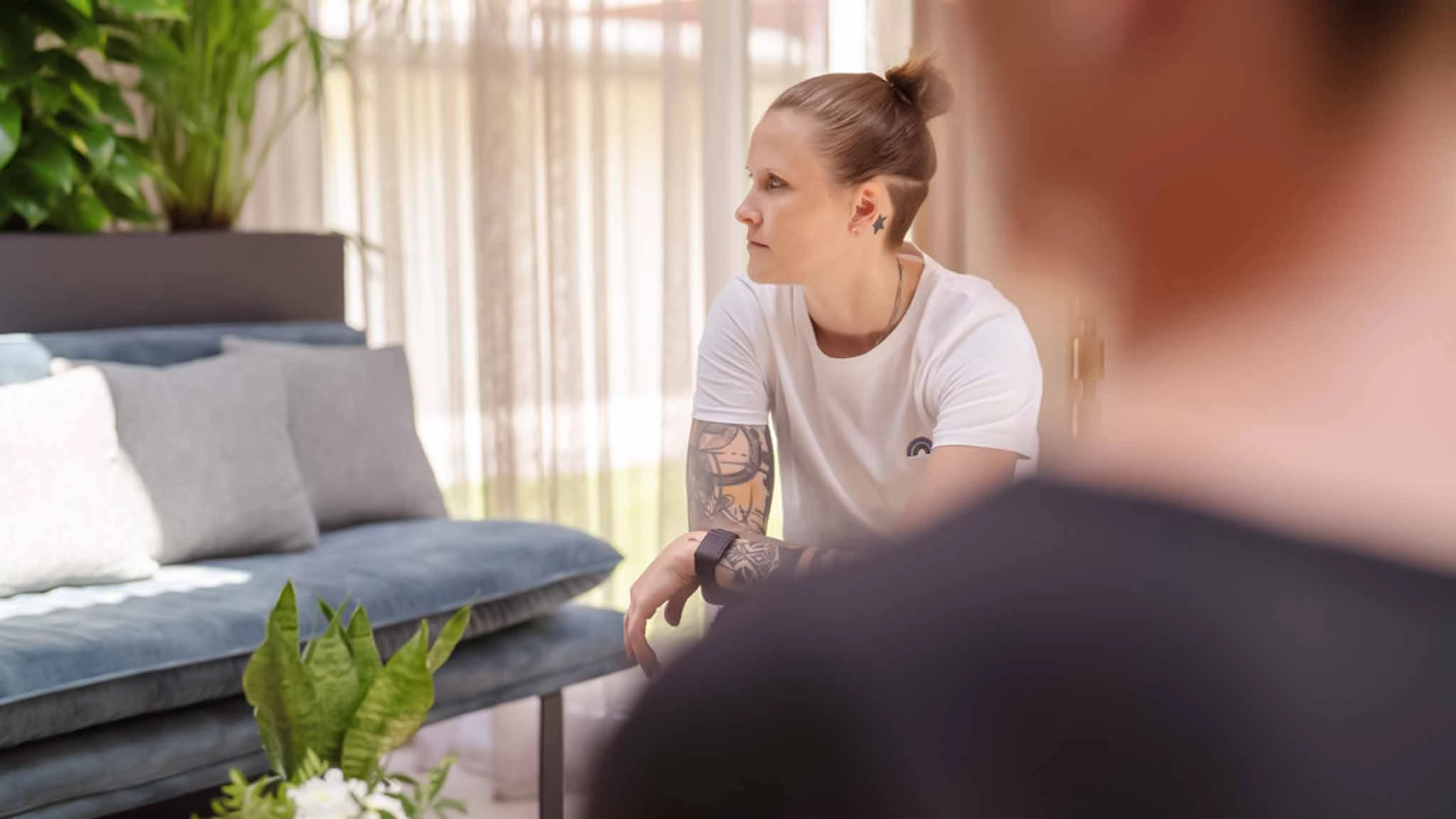 Eine Patientin mit Borderline-Störung sitzt mit anderen Patienten zusammen in einer gemütlichen Lounge.