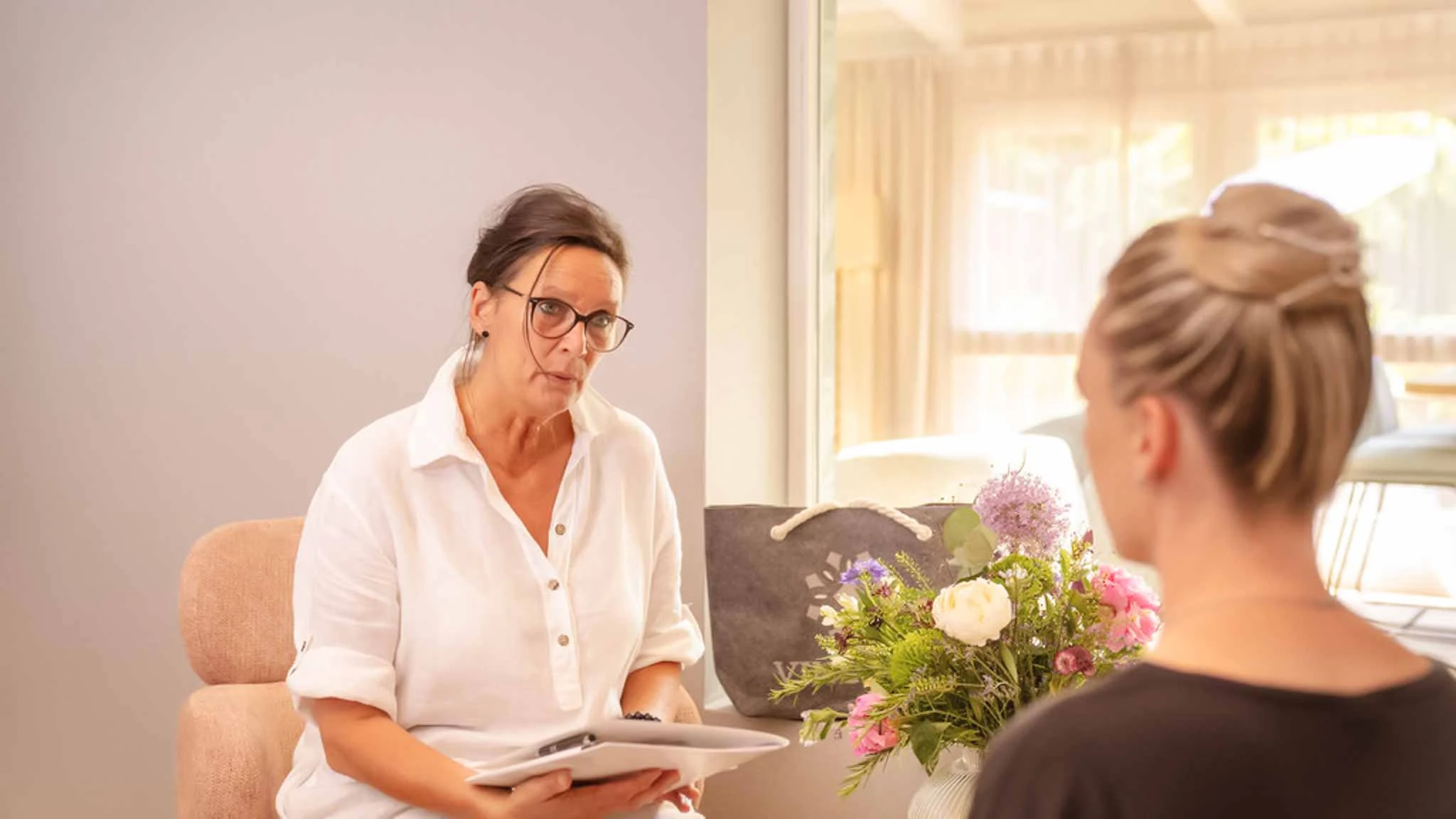 Eine Frau, die unter den Nebenwirkungen der Wechseljahre leidet, sitzt einer Patientenmanagerin gegenüber im Gespräch.