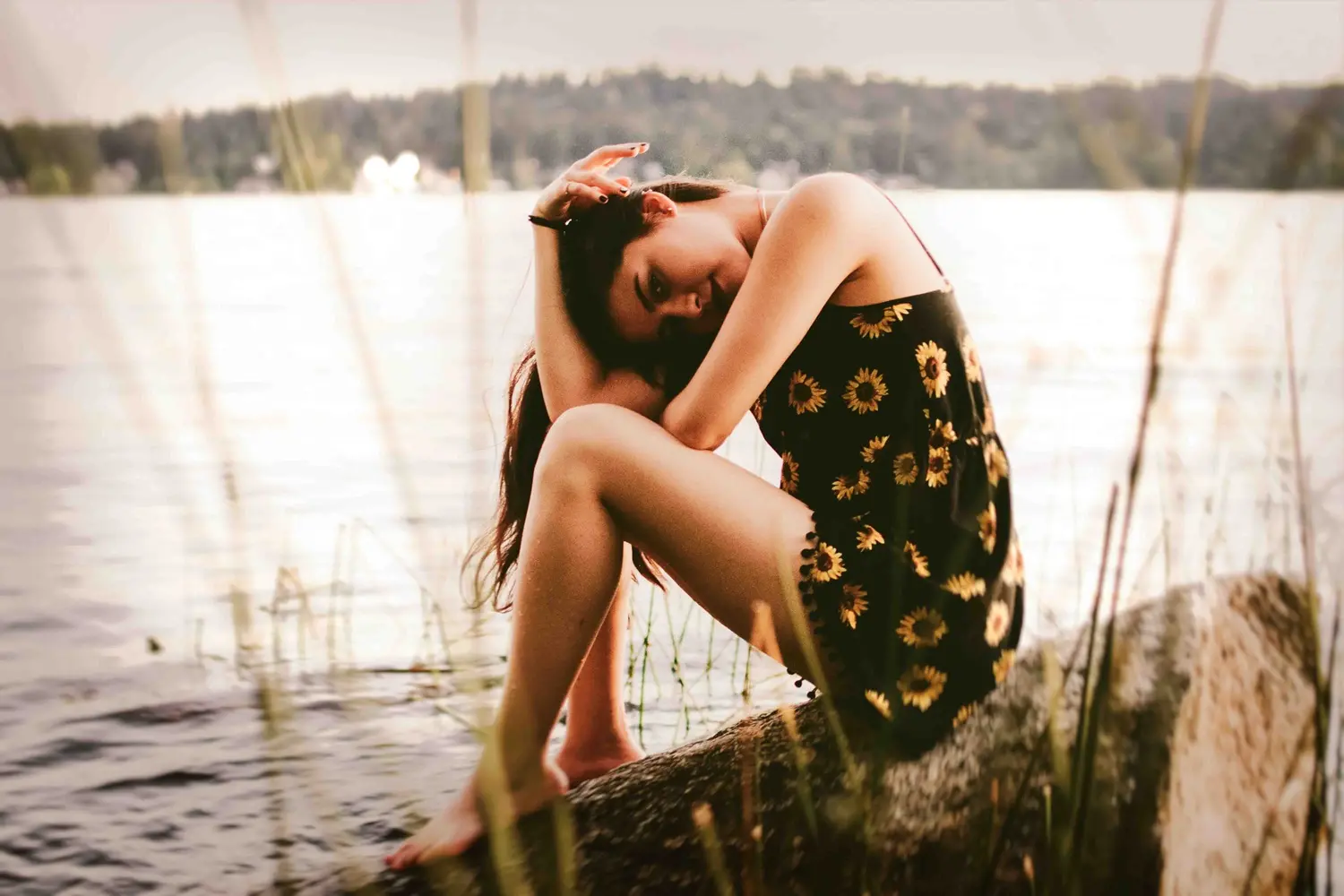 Eine Patientin, die an einer Sommerdepression leidet, sitzt am Ufer eines Flusses.